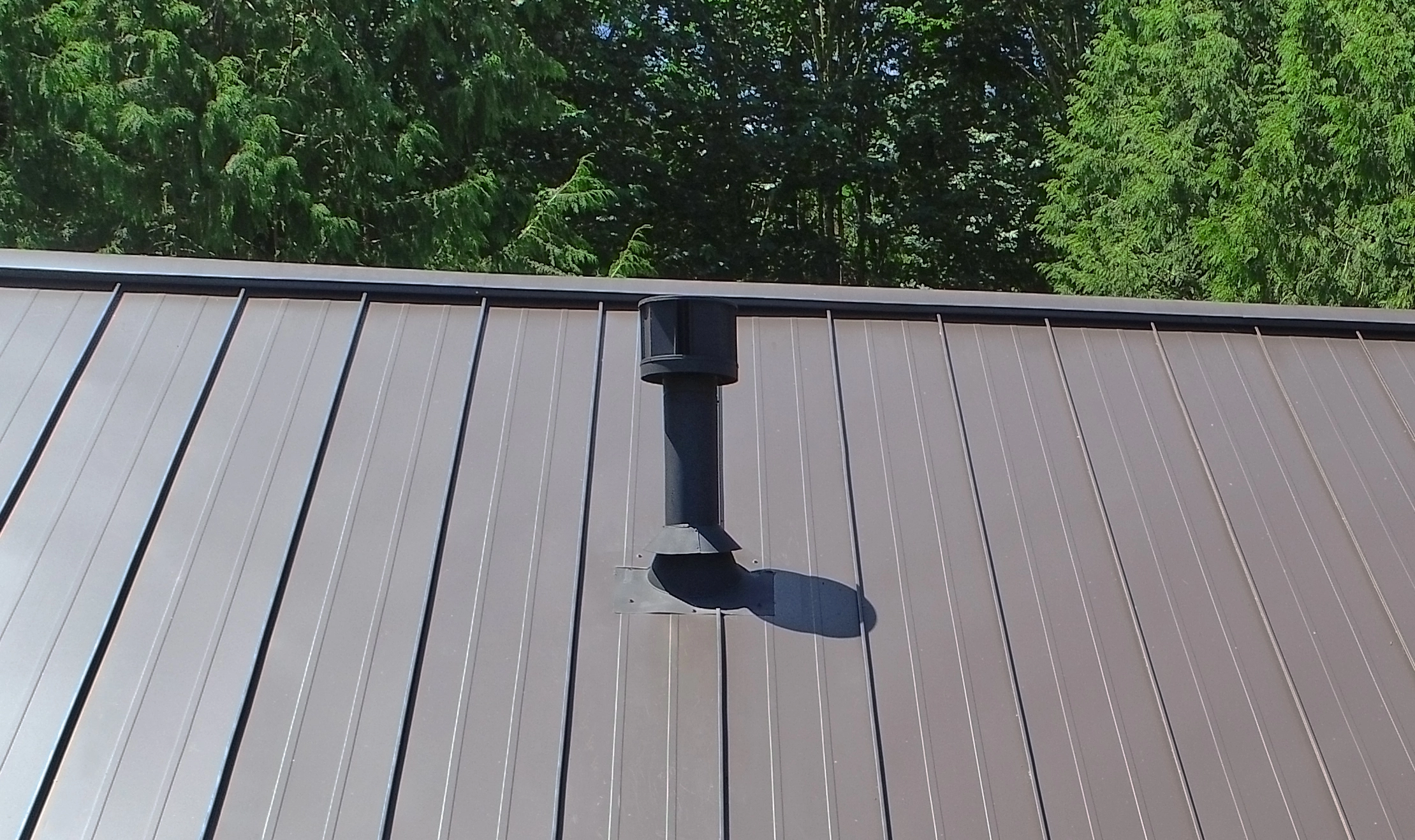 Tudor Brown Interlock Standing Seam aluminum roof on a brown two-storey Tudor home with dormers among tall, Fall City, Washington