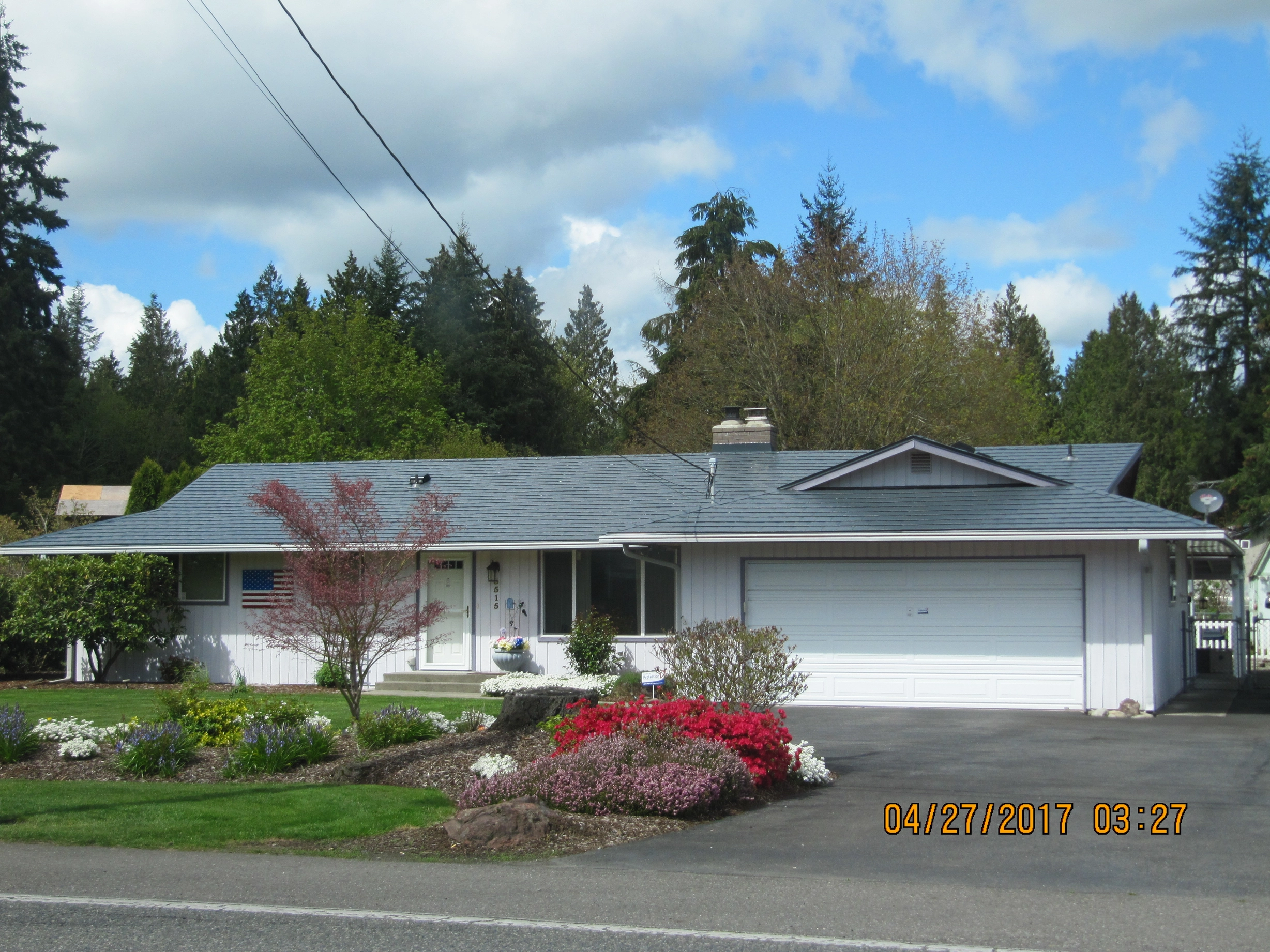 Deep Charcoal Interlock Slate aluminum roof on a Deep Charcoal metal roof on a white ranch home among tall, Marysville, Washington