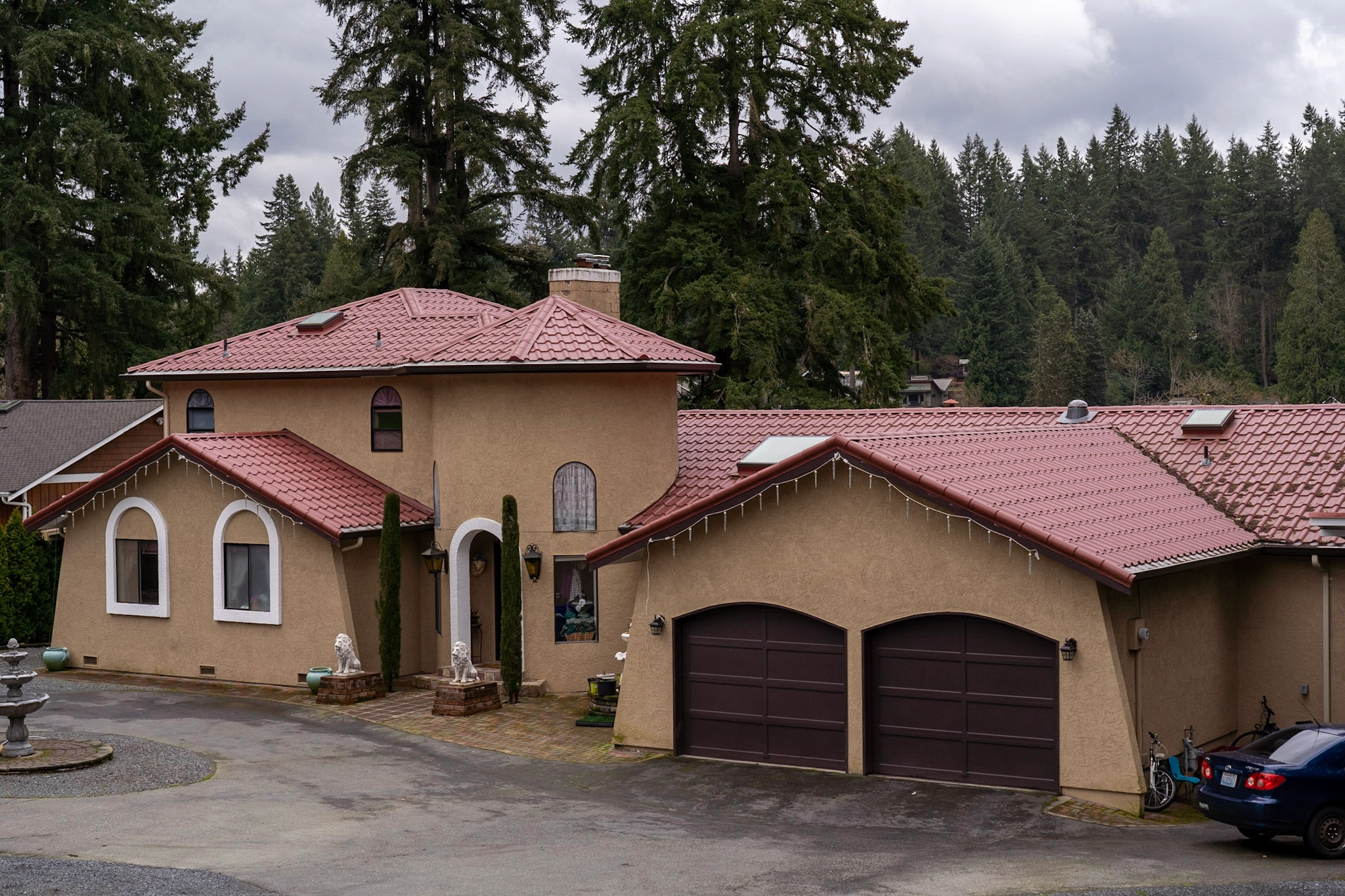 Tile Red Interlock Tile aluminum roof on a tan stucco home with a red metal roof among tall, Woodinville, Washington