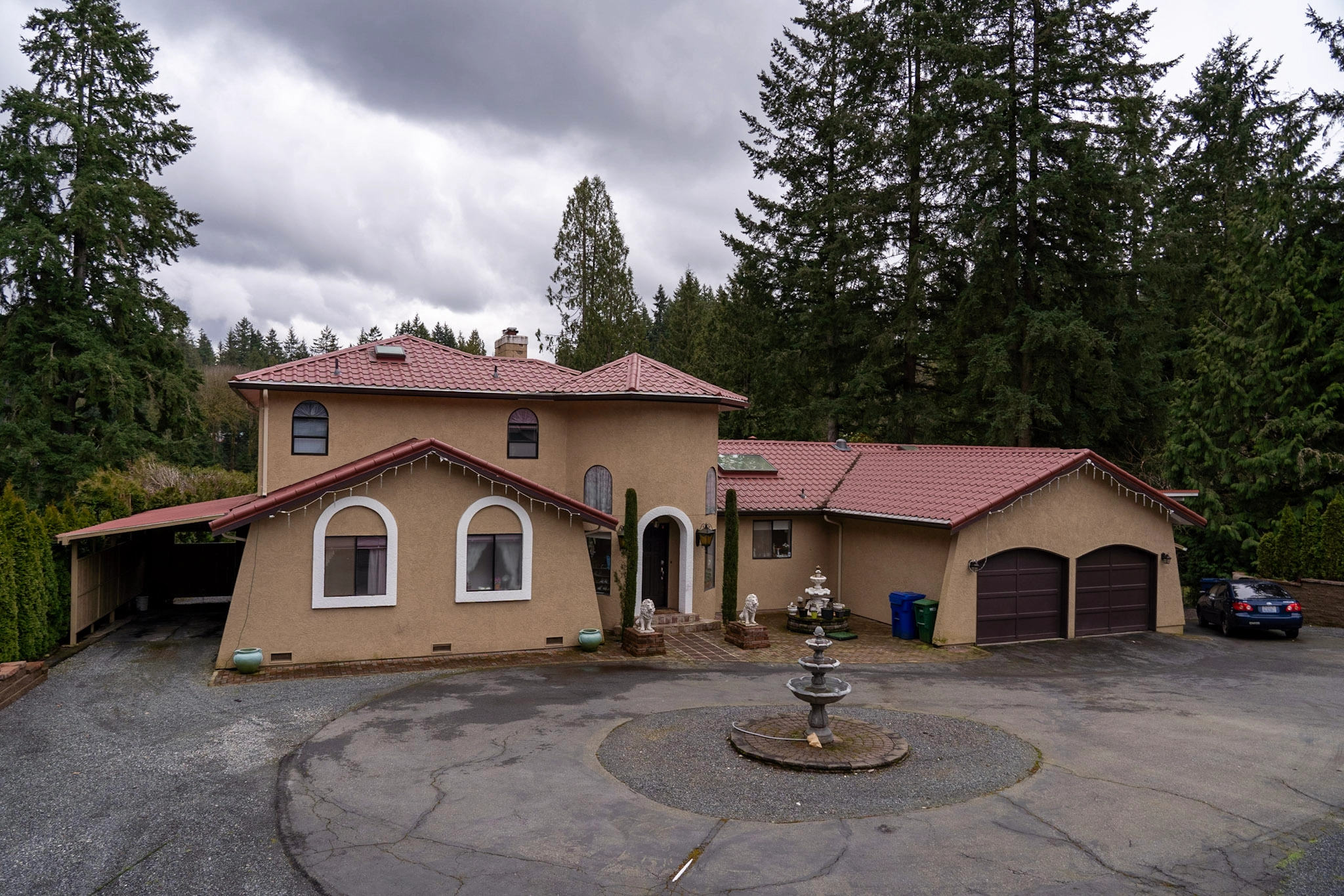 Tile Red Interlock Tile aluminum roof on a tan single-storey Mediterranean home among tall evergreens, Woodinville, Washington