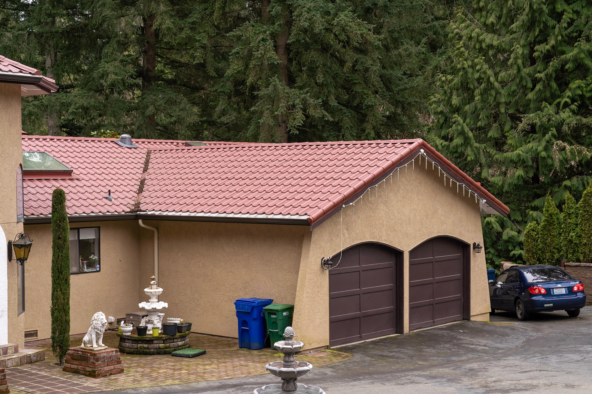 Tile Red Interlock Tile aluminum roof on a tan single-family home with a red tile roof among tall, Woodinville, Washington