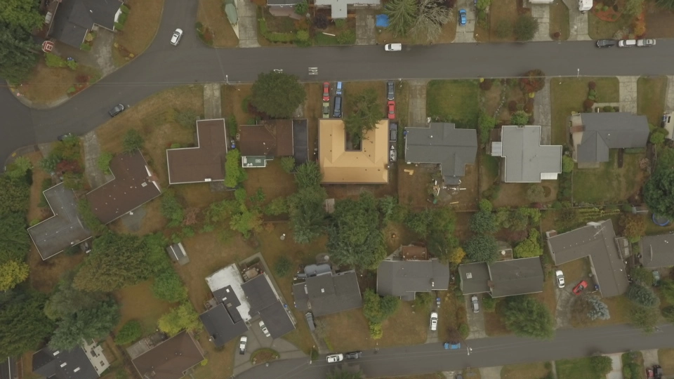 Aged Copper Interlock Cedar Shingle aluminum roof on a beige single-storey home with dormers among green trees, Bellevue, Washington