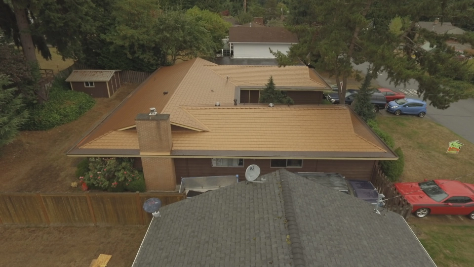 Aged Copper Interlock Cedar Shingle aluminum roof on a brown ranch-style home with a metal roof among tall trees, Bellevue, Washington