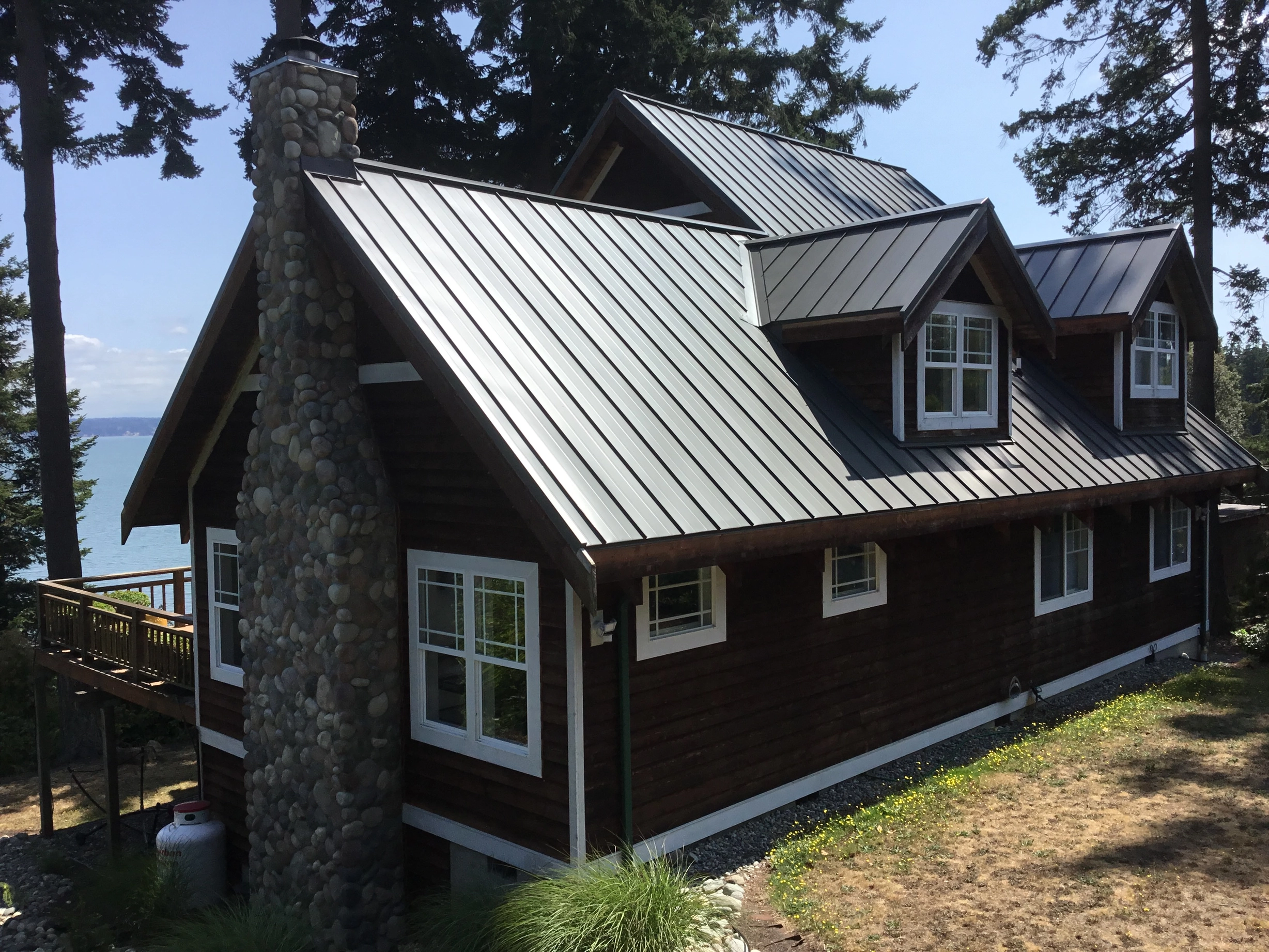 Musket Grey Interlock Standing Seam aluminum roof on a brown two-storey home with dormers near the ocean, Camano Island, Washington