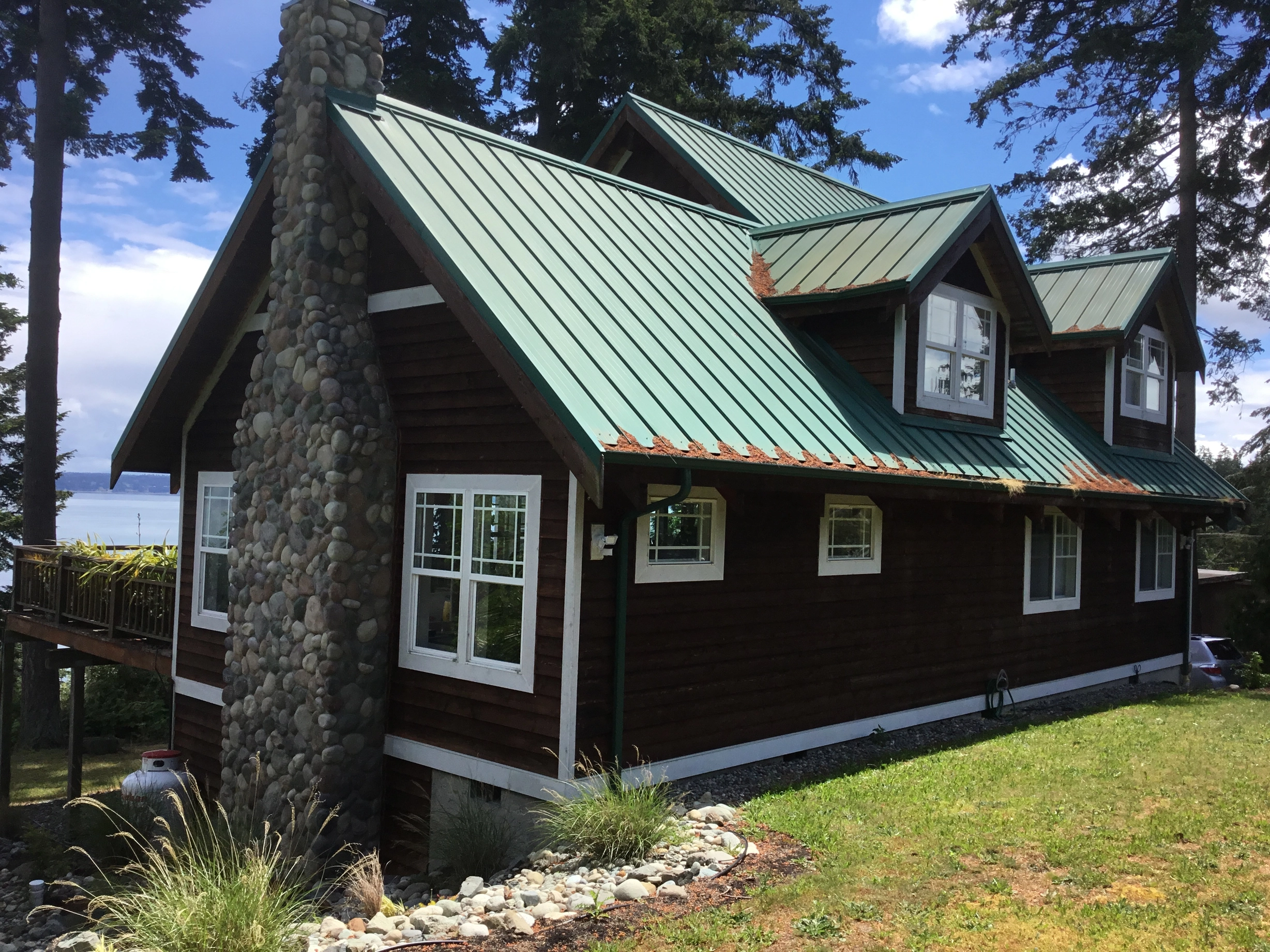 Before: a rusted metal roof on the home, Camano Island, Washington, ahead of a Musket Grey Interlock Standing Seam aluminum roof
