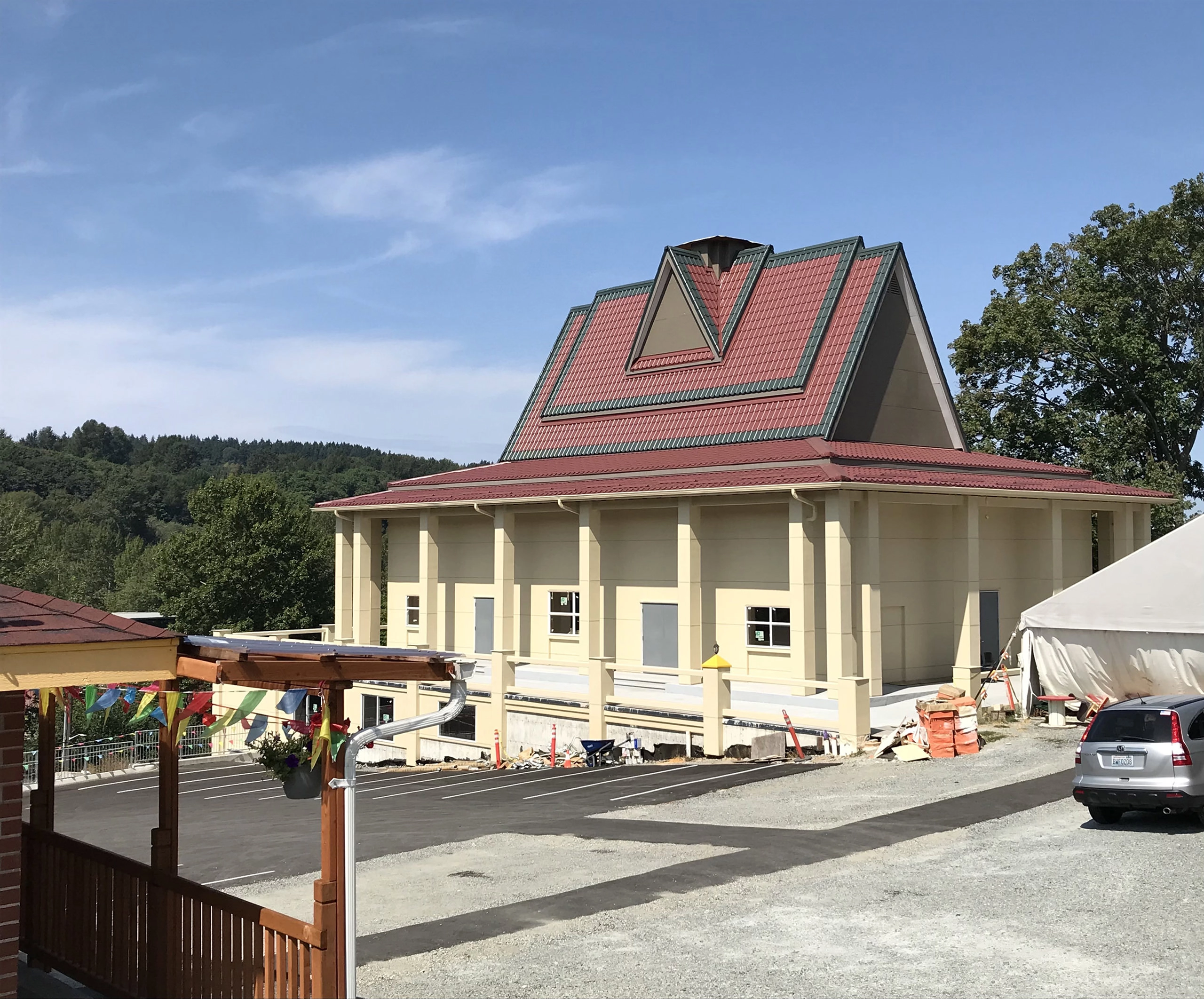 Tile Red Interlock Mediterranean aluminum tile roof on a large institutional building with steep multi-hip profile and dormers, set against forested hills in Seattle, WA.