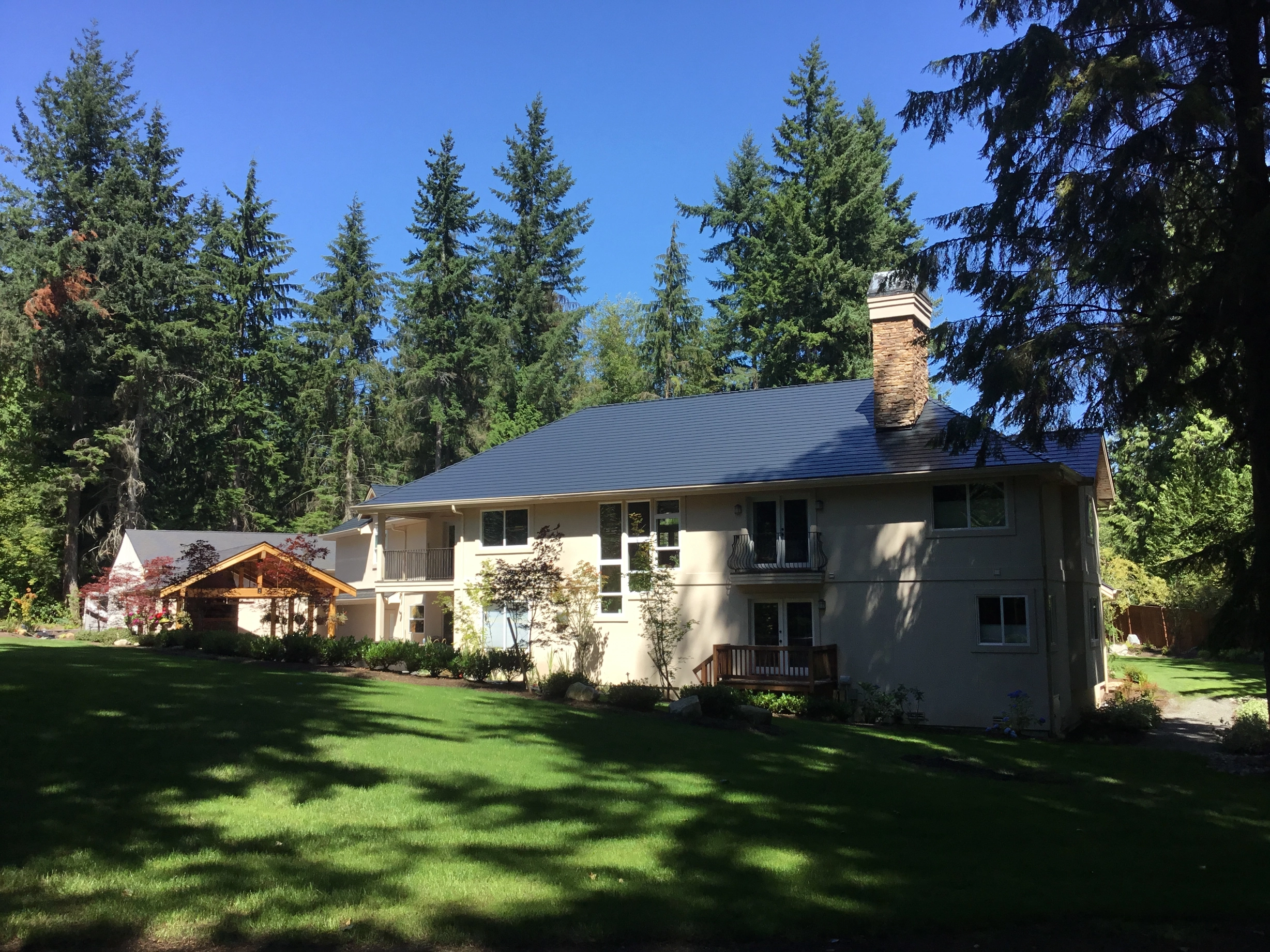 Black Interlock Slate aluminum roof on a white modern home with large windows among tall pines, Bothell, Washington