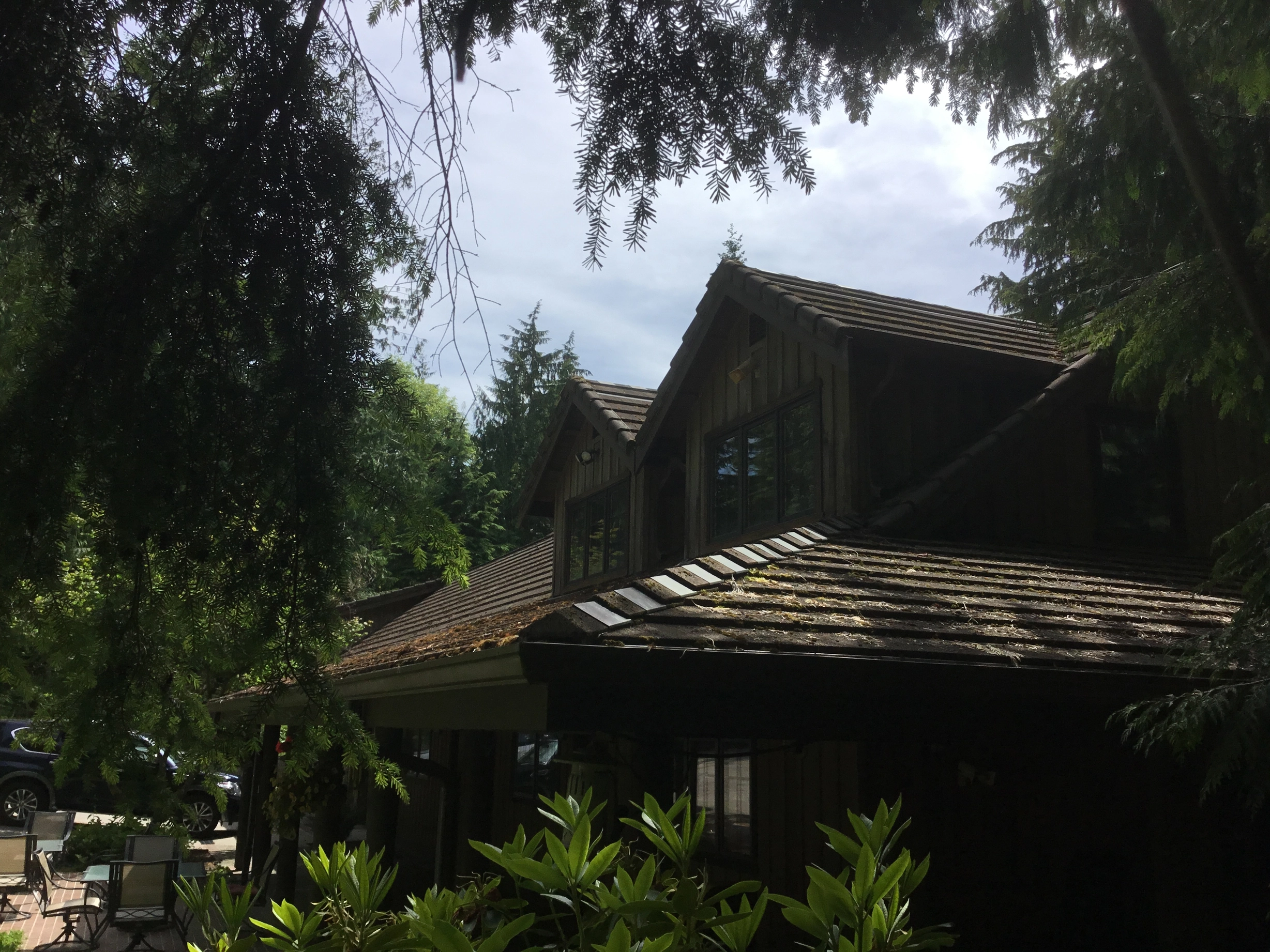 Before: a concrete tile roof with broken tiles on the home, Preston, Washington, ahead of a Hunter Green Interlock Standing Seam aluminum roof