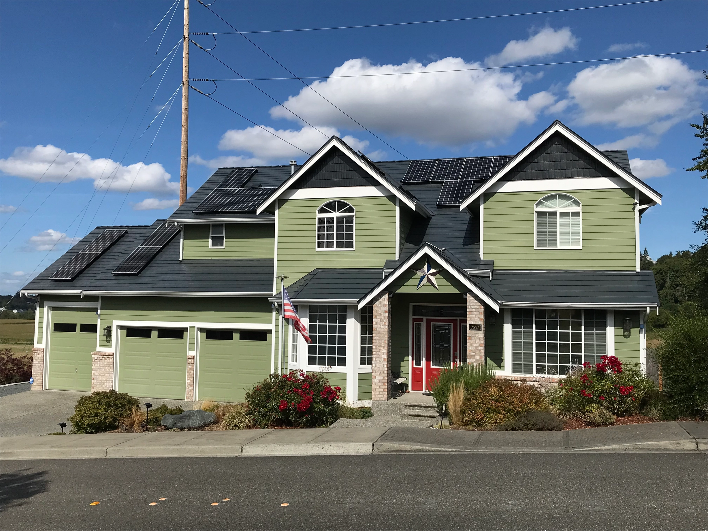 Deep Charcoal Interlock Slate aluminum roof on a two-storey home with green siding and dark roof in a, Marysville, Washington