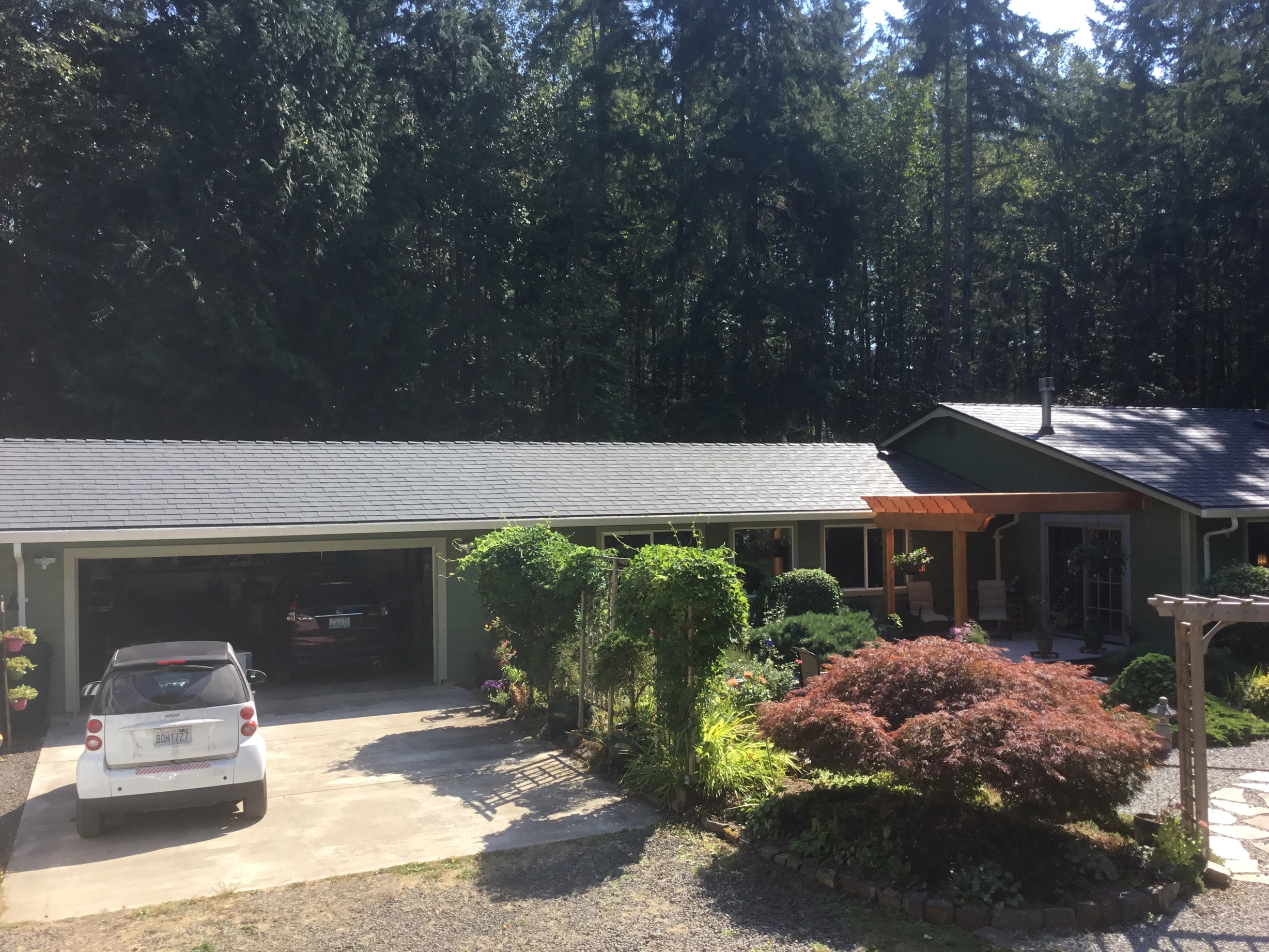 Deep Charcoal Interlock Slate aluminum roof on a green single-storey home with a metal roof among tall, Poulsbo, Washington