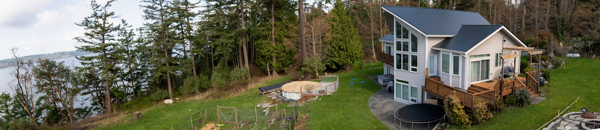 Black Interlock Slate aluminum roof on a white home with a black metal roof in a wooded area, Langley, Washington