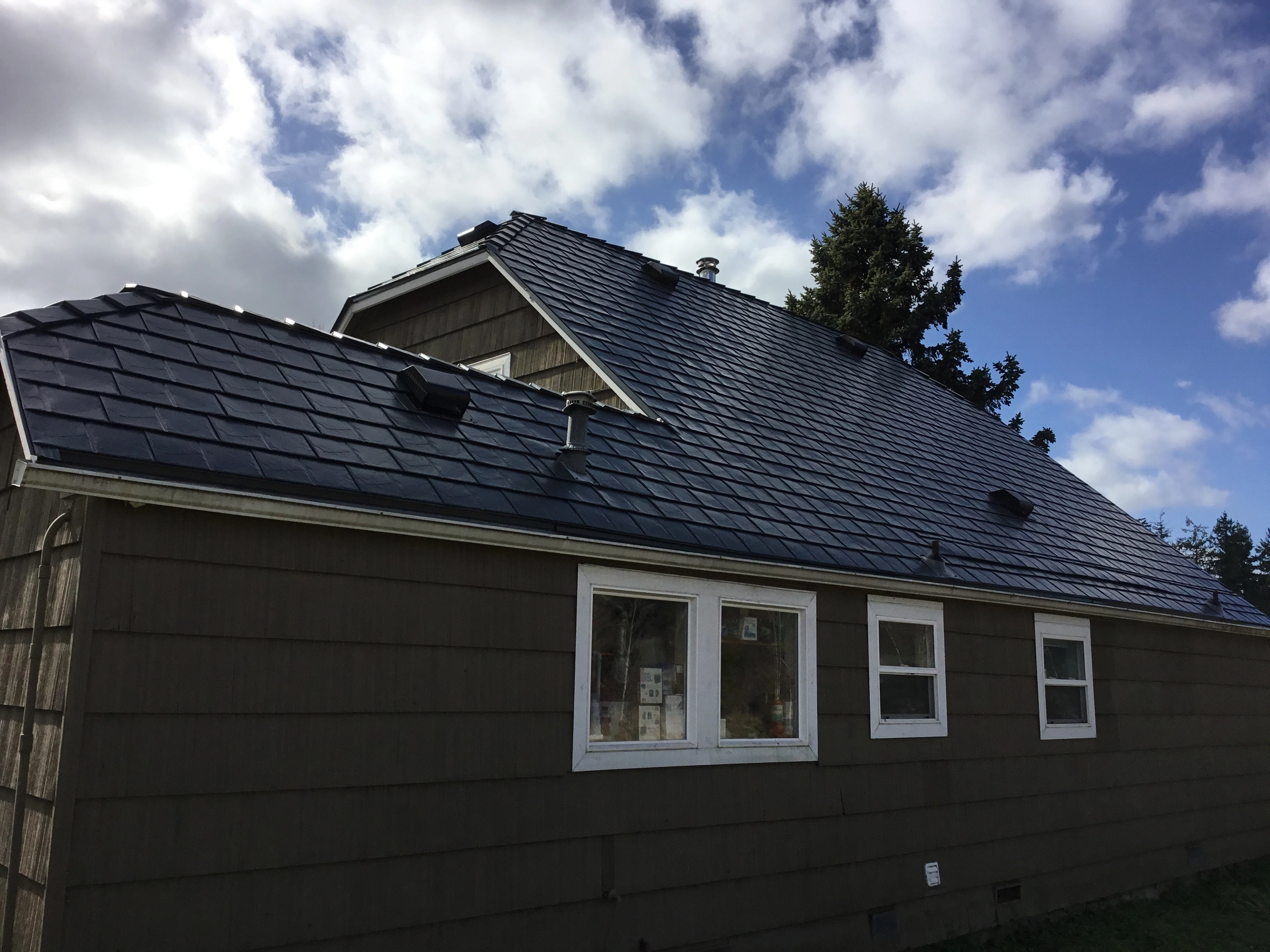 Deep Charcoal Interlock Slate aluminum roof on a dark brown single-family home with a metal roof in an, Tacoma, Washington