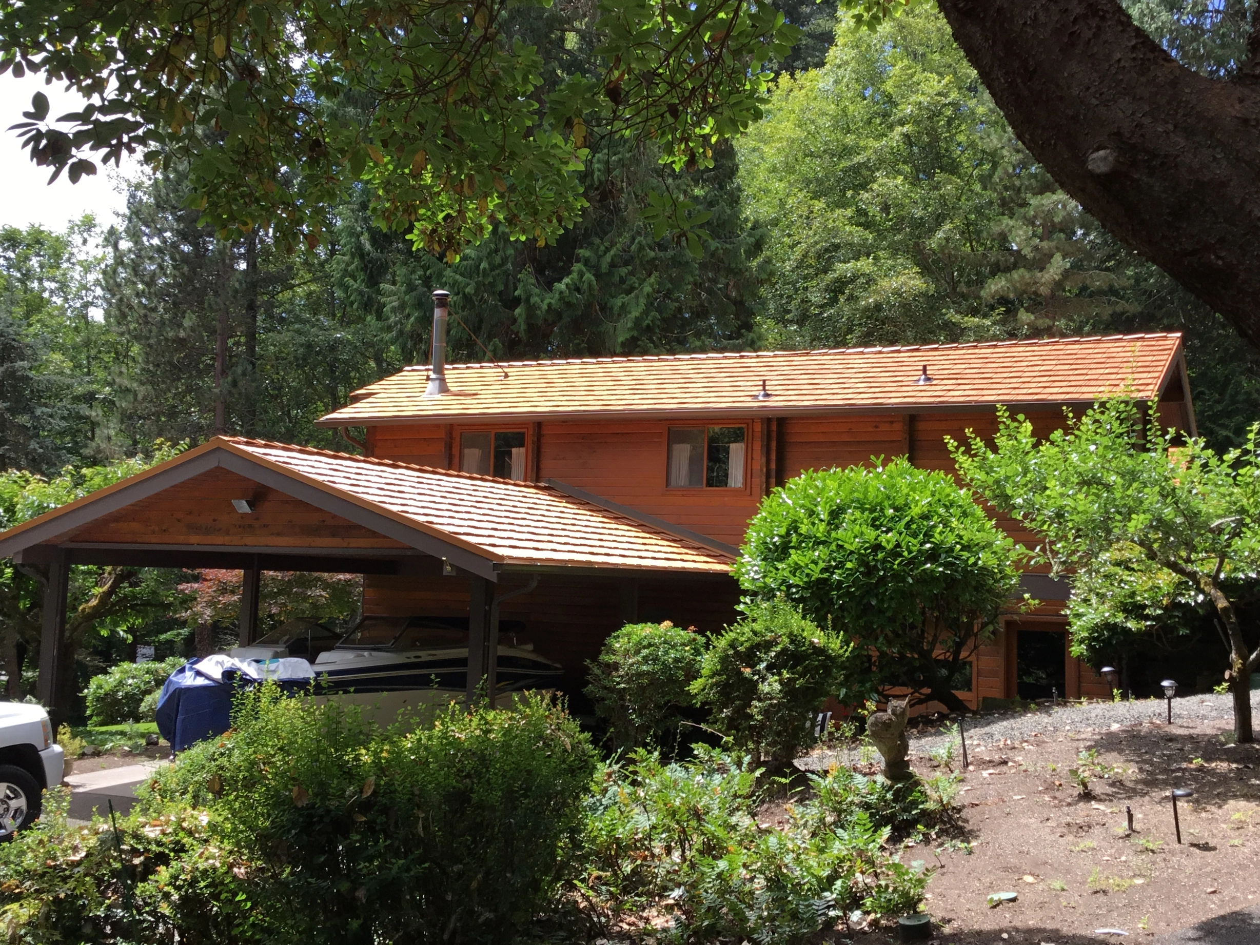 Copper Penny Interlock Shake aluminum roof on a red ranch-style home with a gable roof among trees, Bainbridge Island, Washington