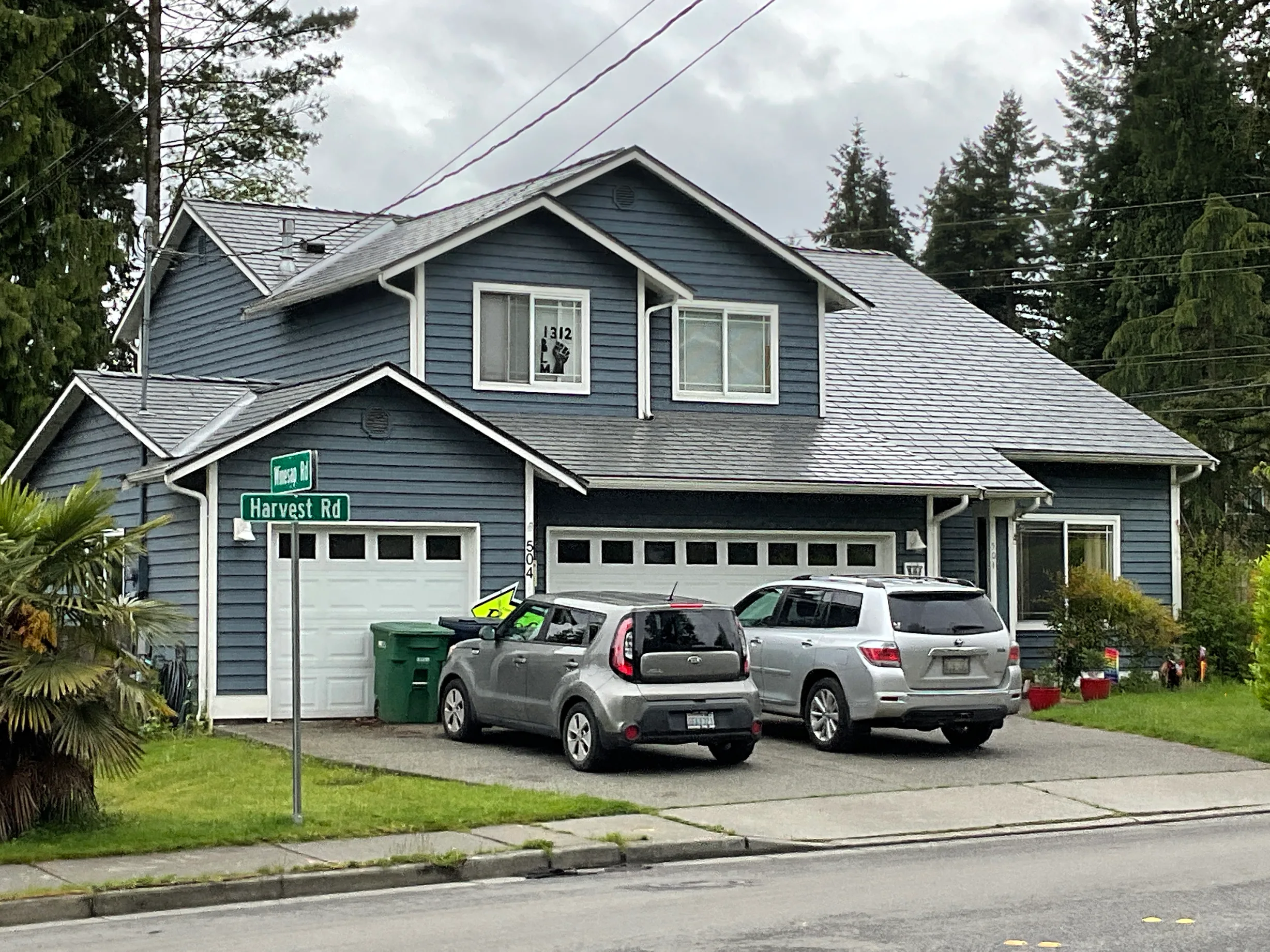 Musket Grey Interlock Slate aluminum roof on a grey two-storey craftsman home with a garage among tall, Bothell, Washington