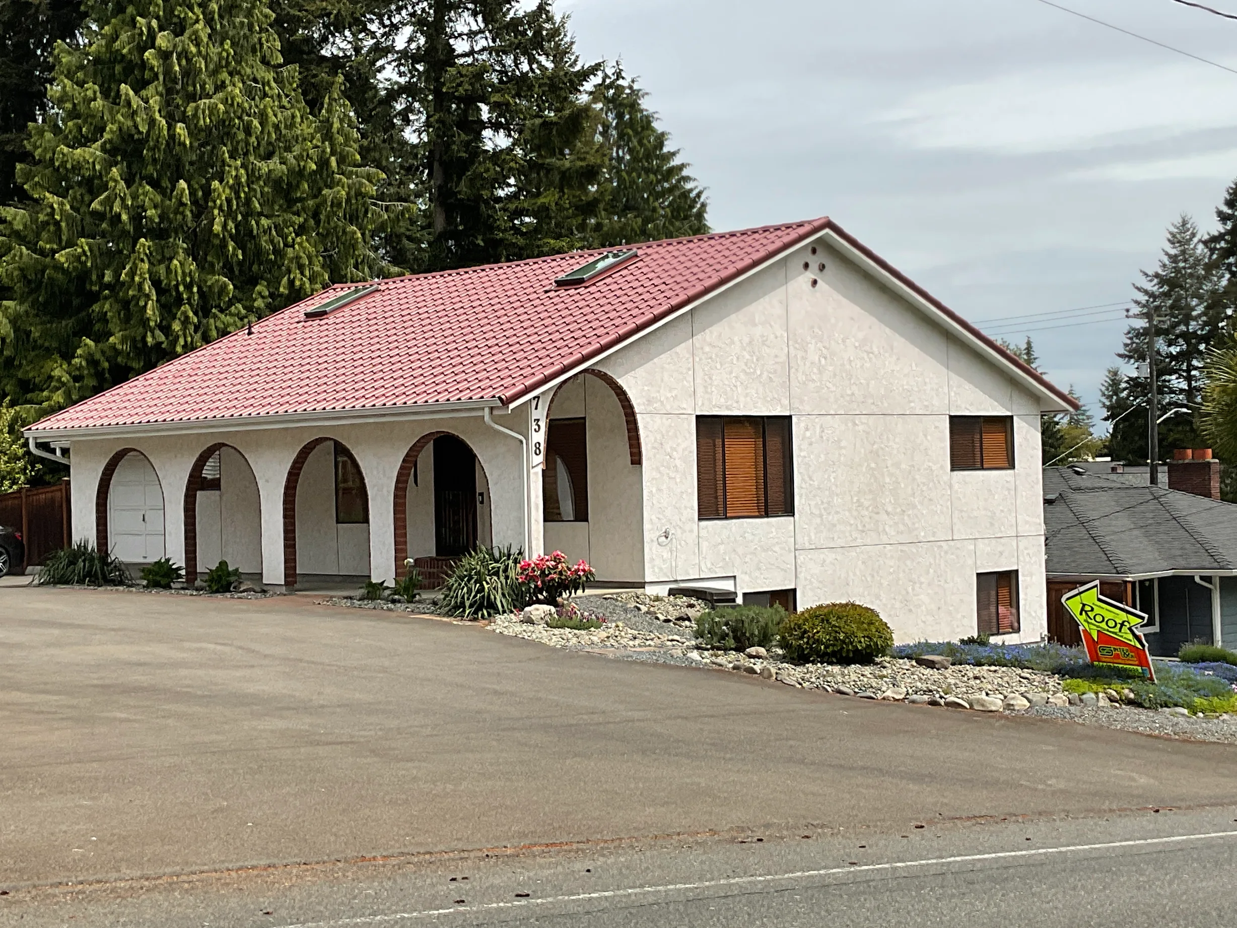 Tile Red Interlock Tile aluminum roof on a white single-family home with red tile roof in a forested, Shoreline, Washington