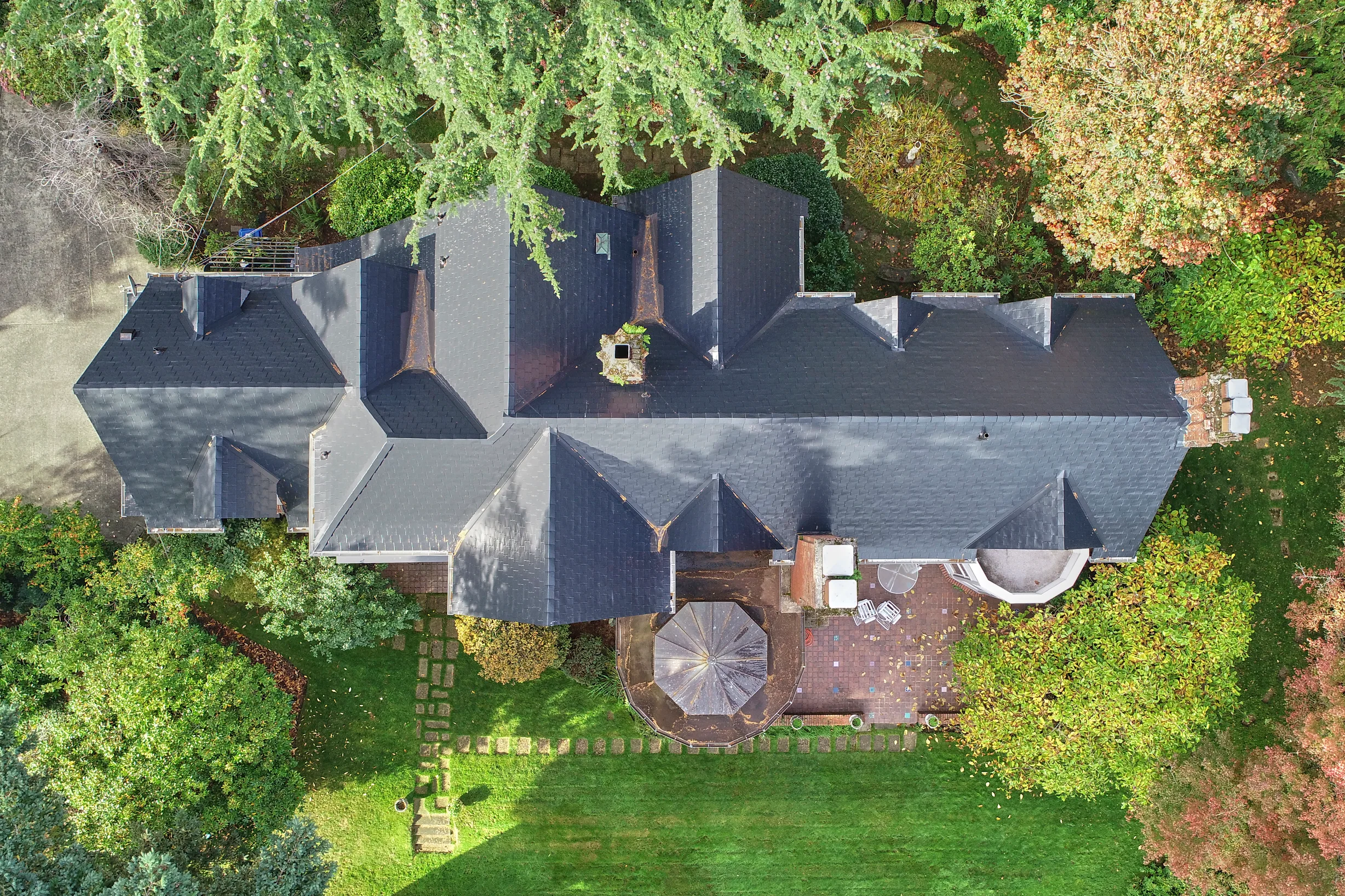 Black Interlock Slate aluminum roof on a two-storey home with a slate roof and dormers among tall, Seattle, Washington