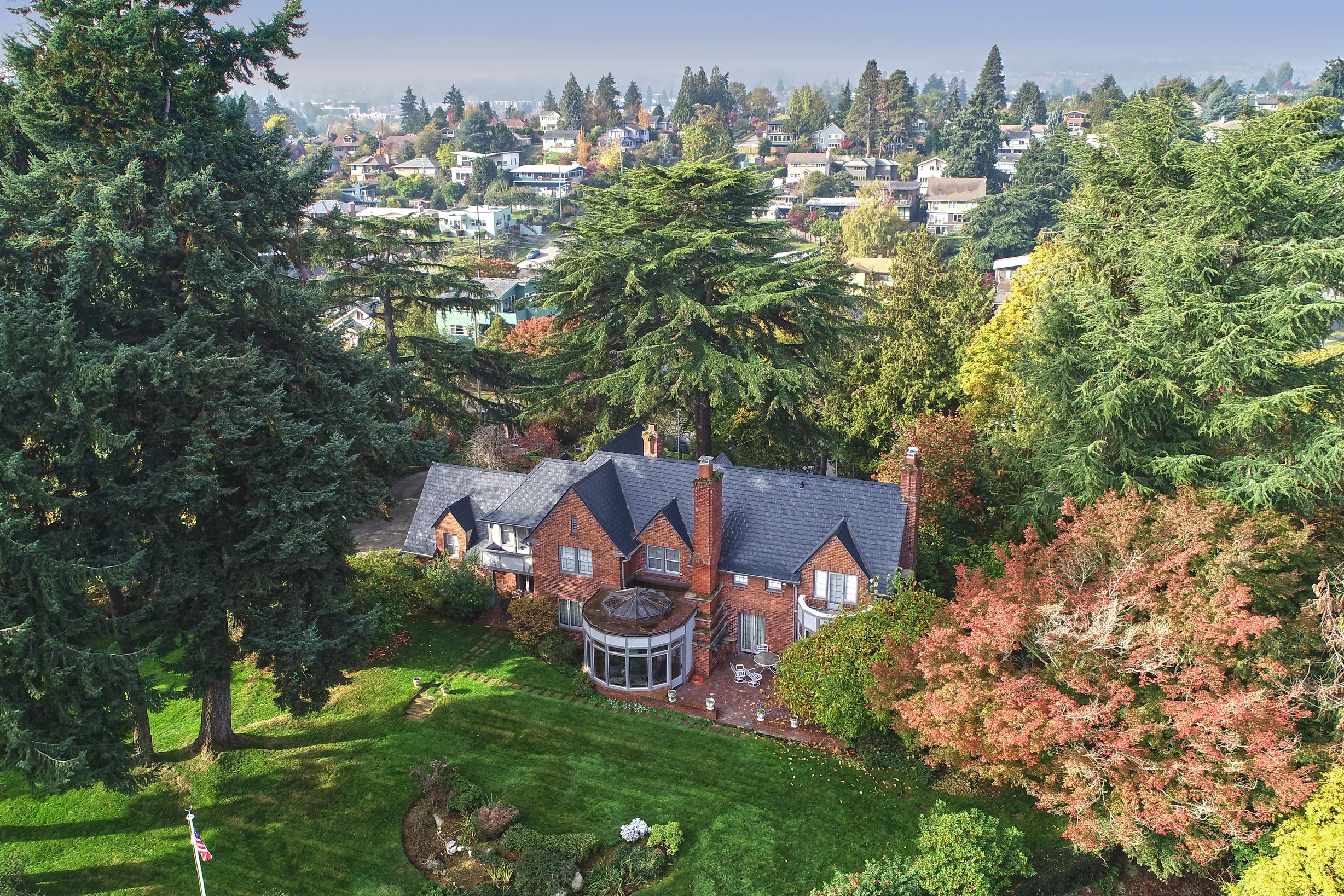 Black Interlock Slate aluminum roof on a red brick house with a black metal roof among tall trees, Seattle, Washington