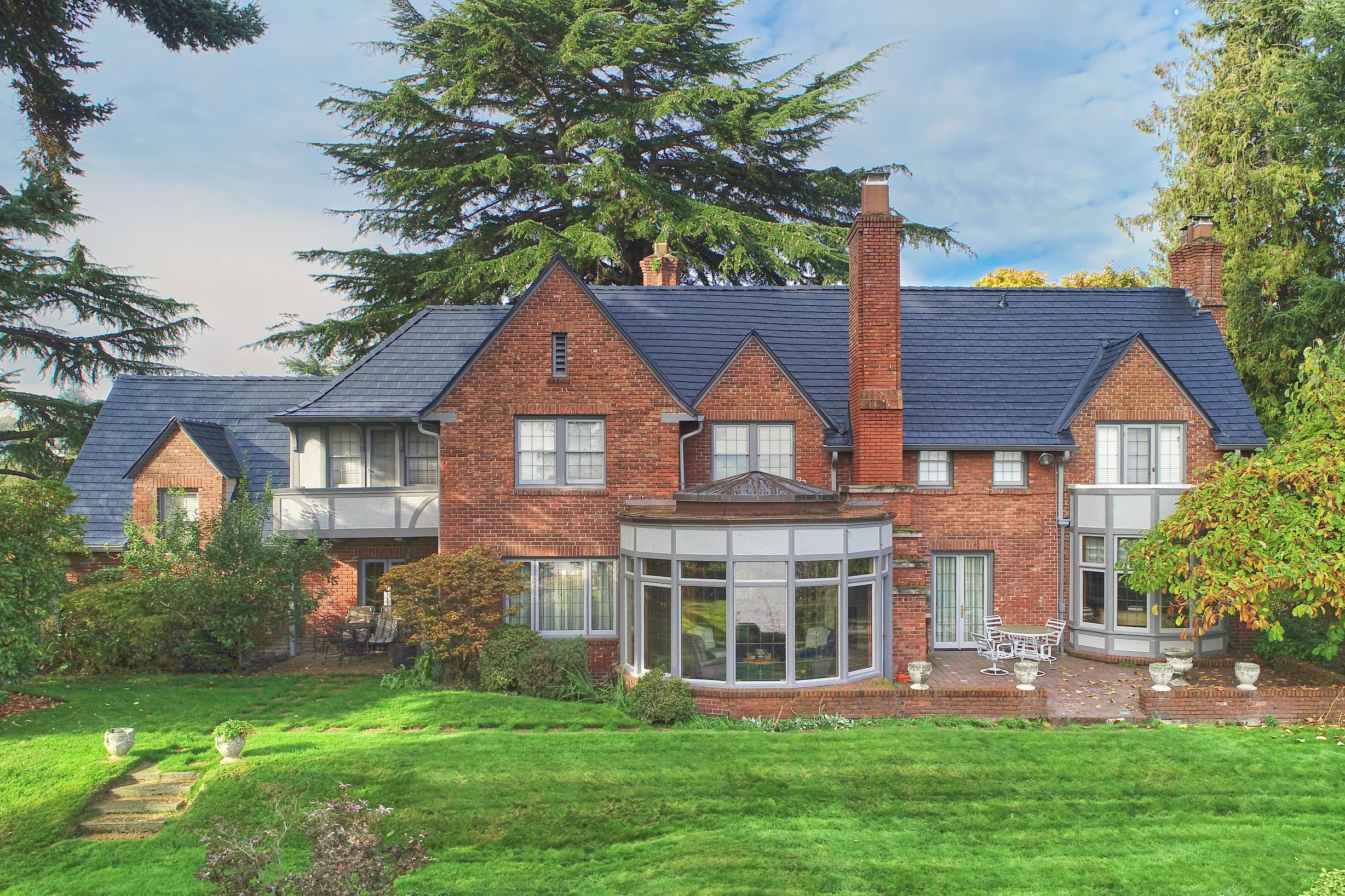 Black Interlock Slate aluminum roof on a red brick Tudor home with dormers in a forested suburban, Seattle, Washington