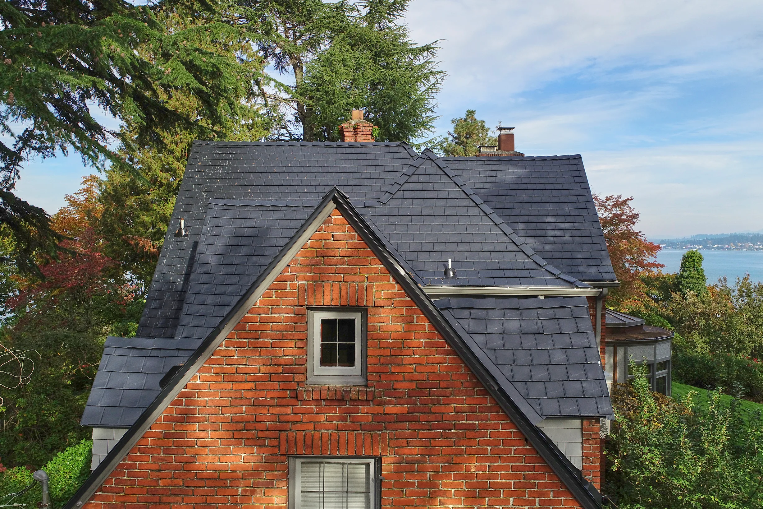 Black Interlock Slate aluminum roof on a red brick two-storey craftsman home with dormers among, Seattle, Washington