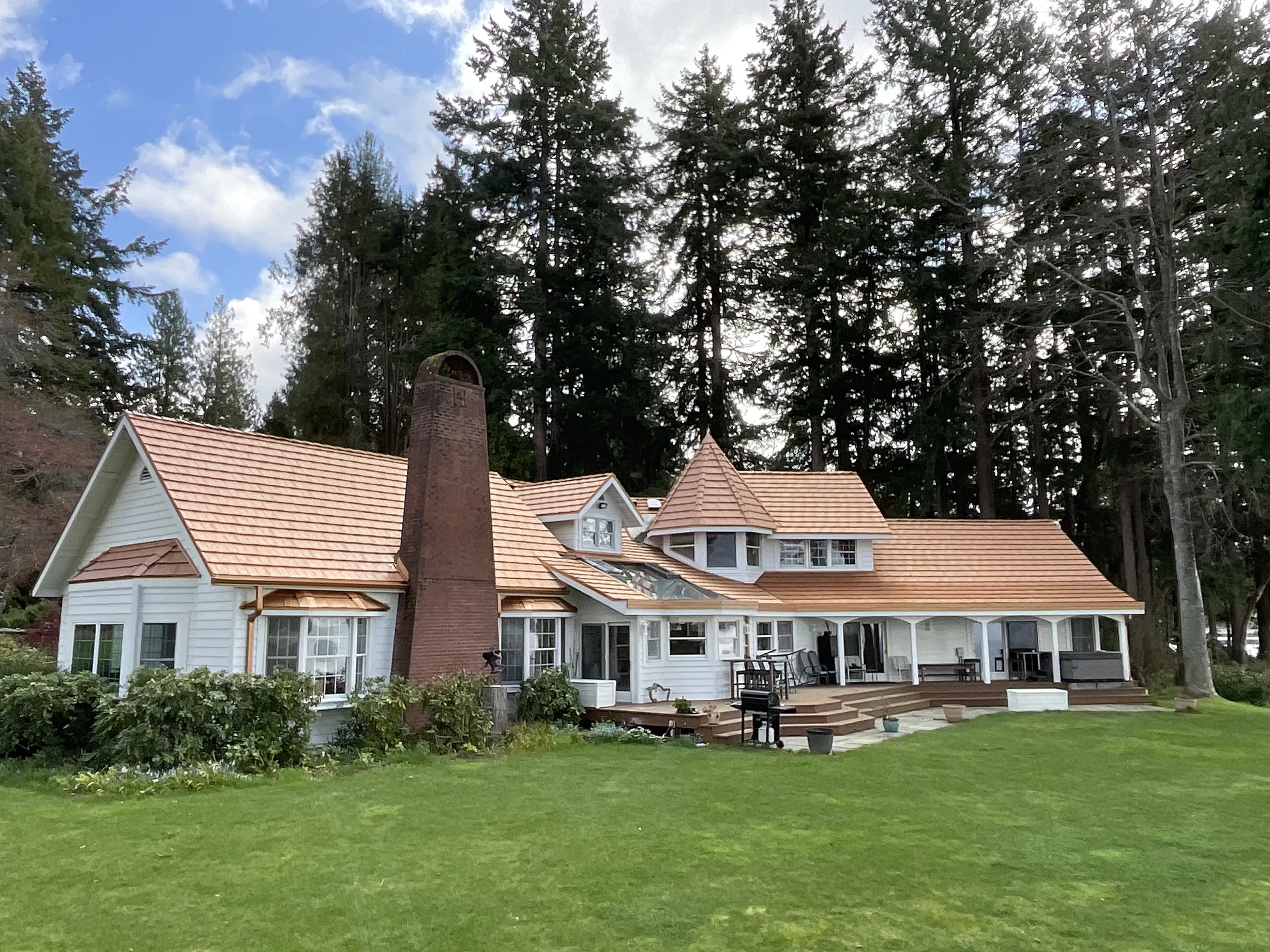 Copper Penny Interlock Shake aluminum roof on a white cottage with a copper penny metal roof among tall, Bremerton, Washington