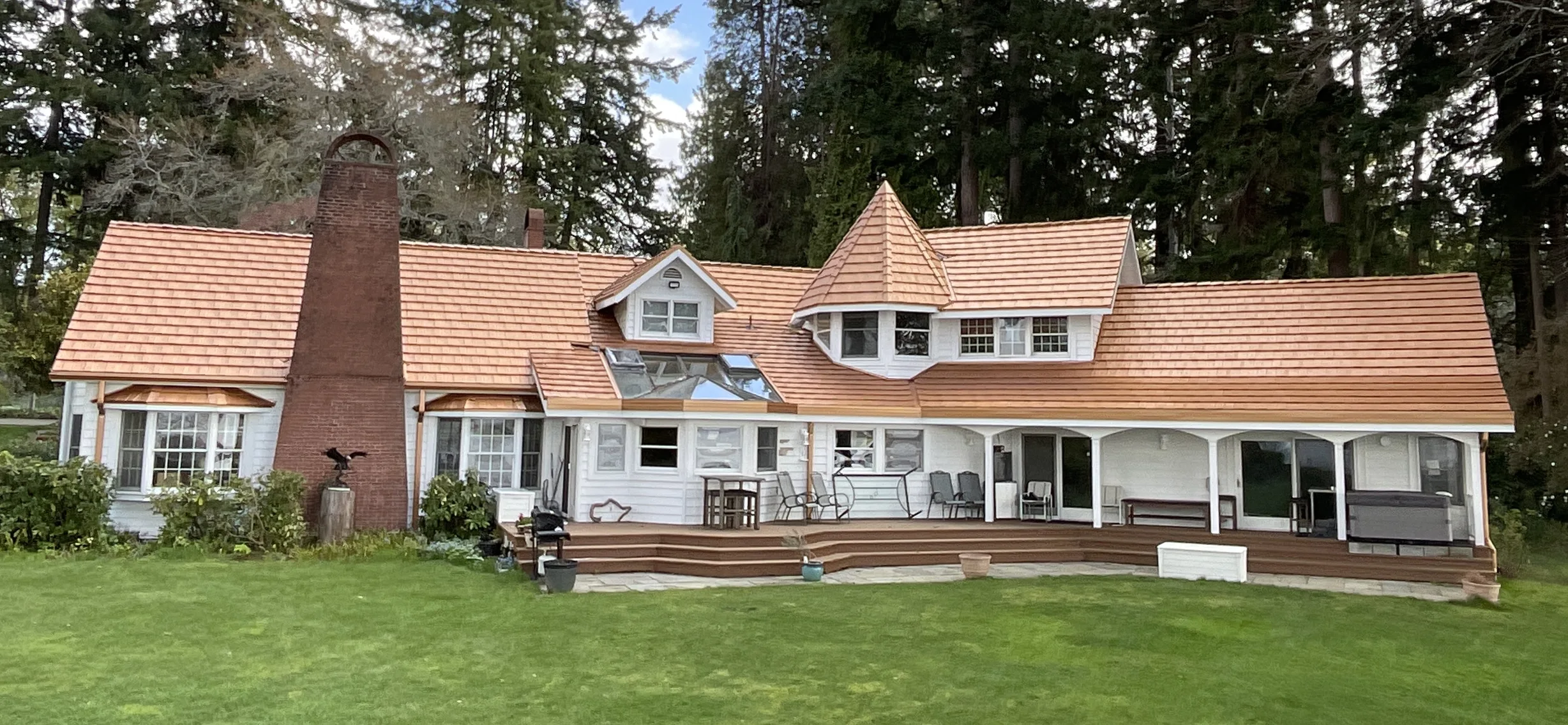 Copper Penny Interlock Shake aluminum roof on a white two-storey Colonial home with dormers among tall, Bremerton, Washington