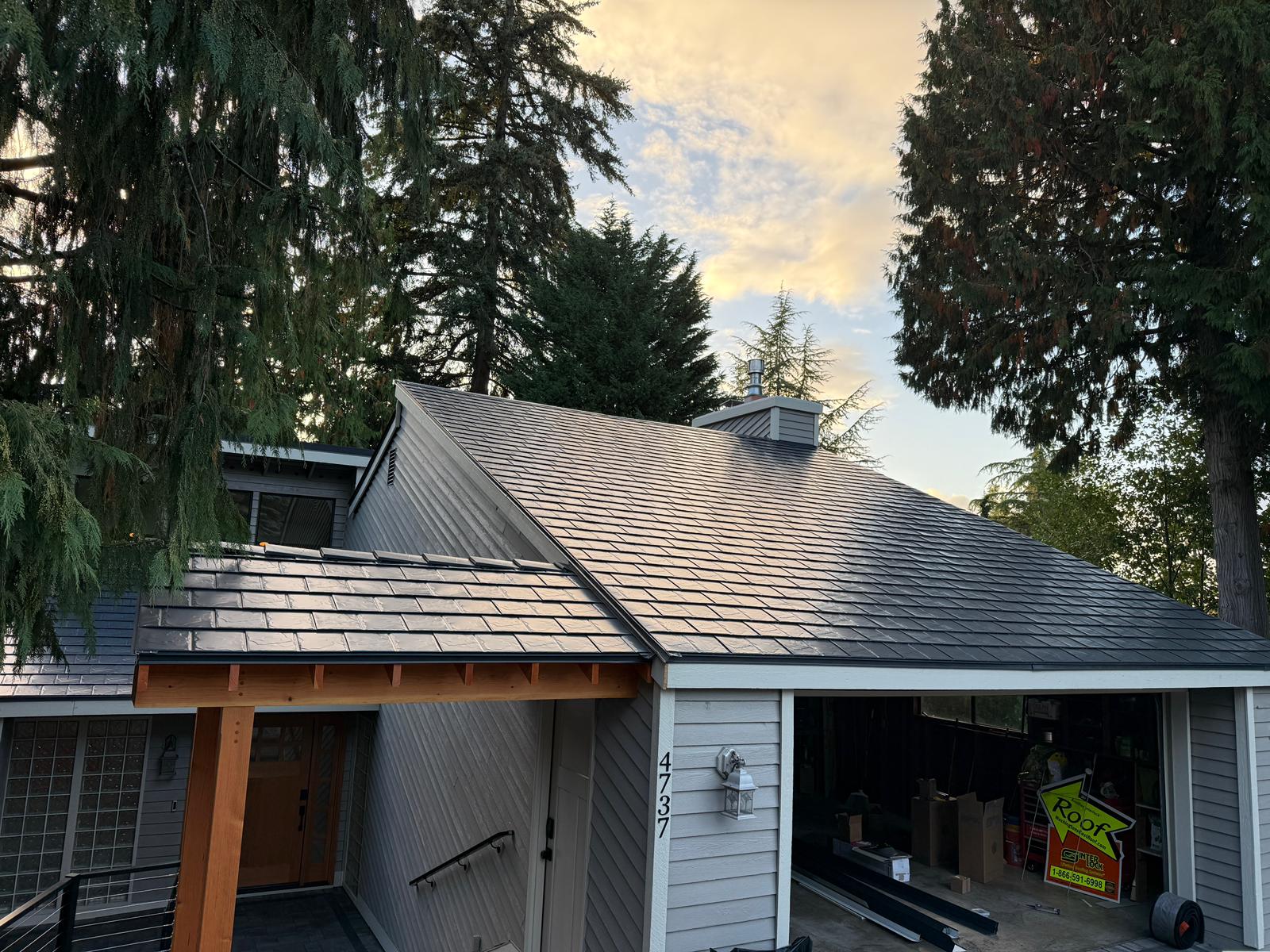 Deep charcoal Interlock aluminum slate metal roof on a 1.5-story Craftsman home in Bellevue WA, showing complex hip lines, chimney, and cedar soffit details.