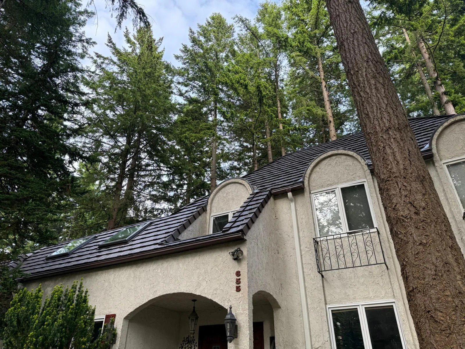 Colonial Brown Interlock Shake aluminum roof on a tan single-storey home with a metal roof among tall, Bellingham, Washington