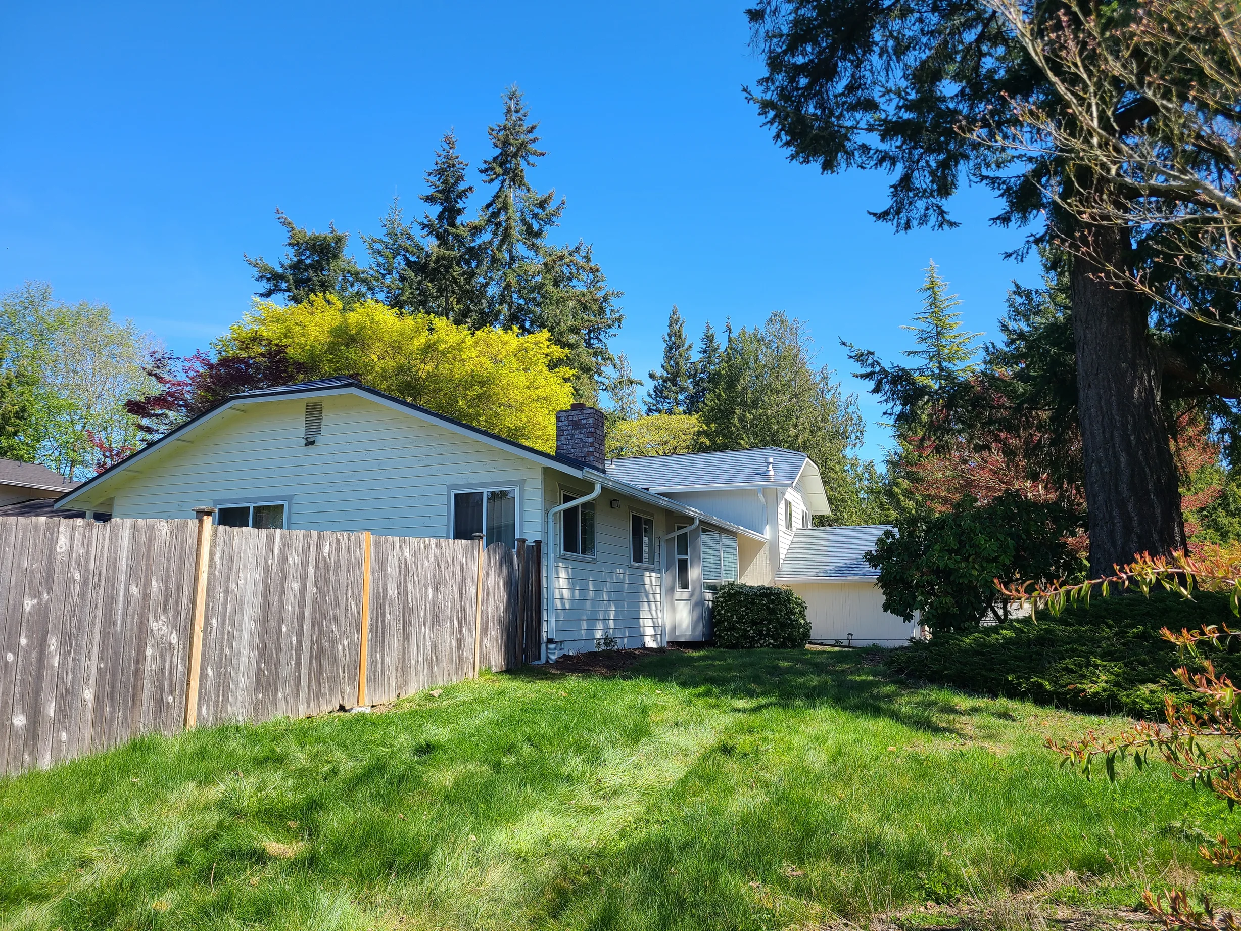 Deep Charcoal Interlock Slate aluminum roof on a white ranch home with a metal roof among green trees, Lynnwood, Washington