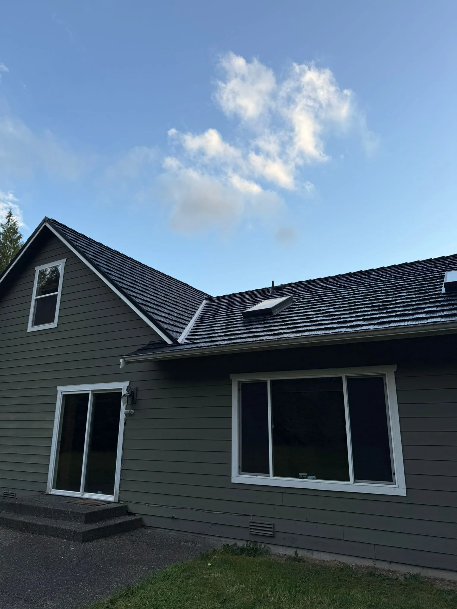 Black Interlock Shake aluminum roof on a dark grey home with a gable and dormers among tall trees, Marysville, Washington