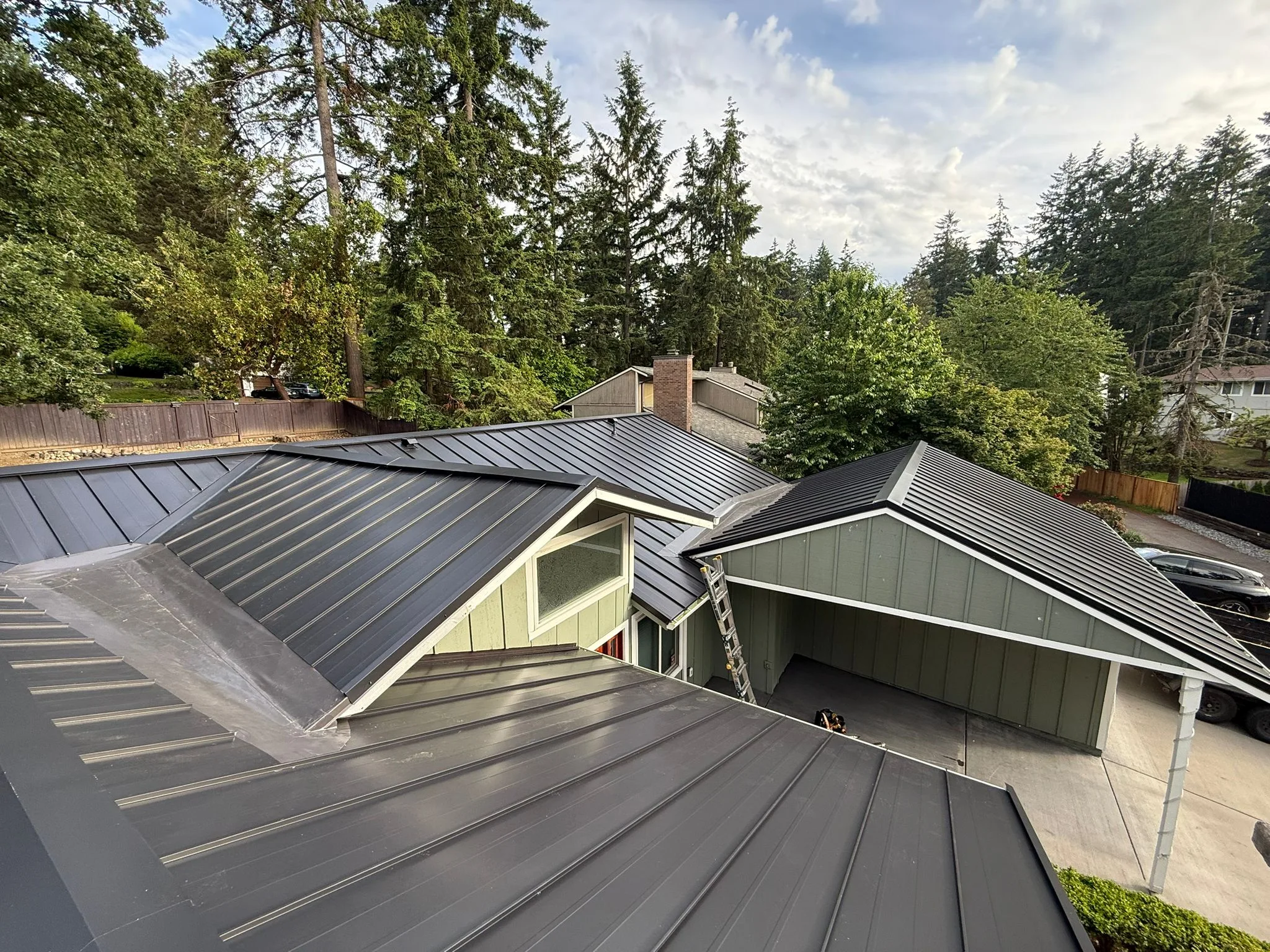 Black Interlock Standing Seam aluminum roof on a modern home with a black metal roof in a forested setting, Lakewood, Washington