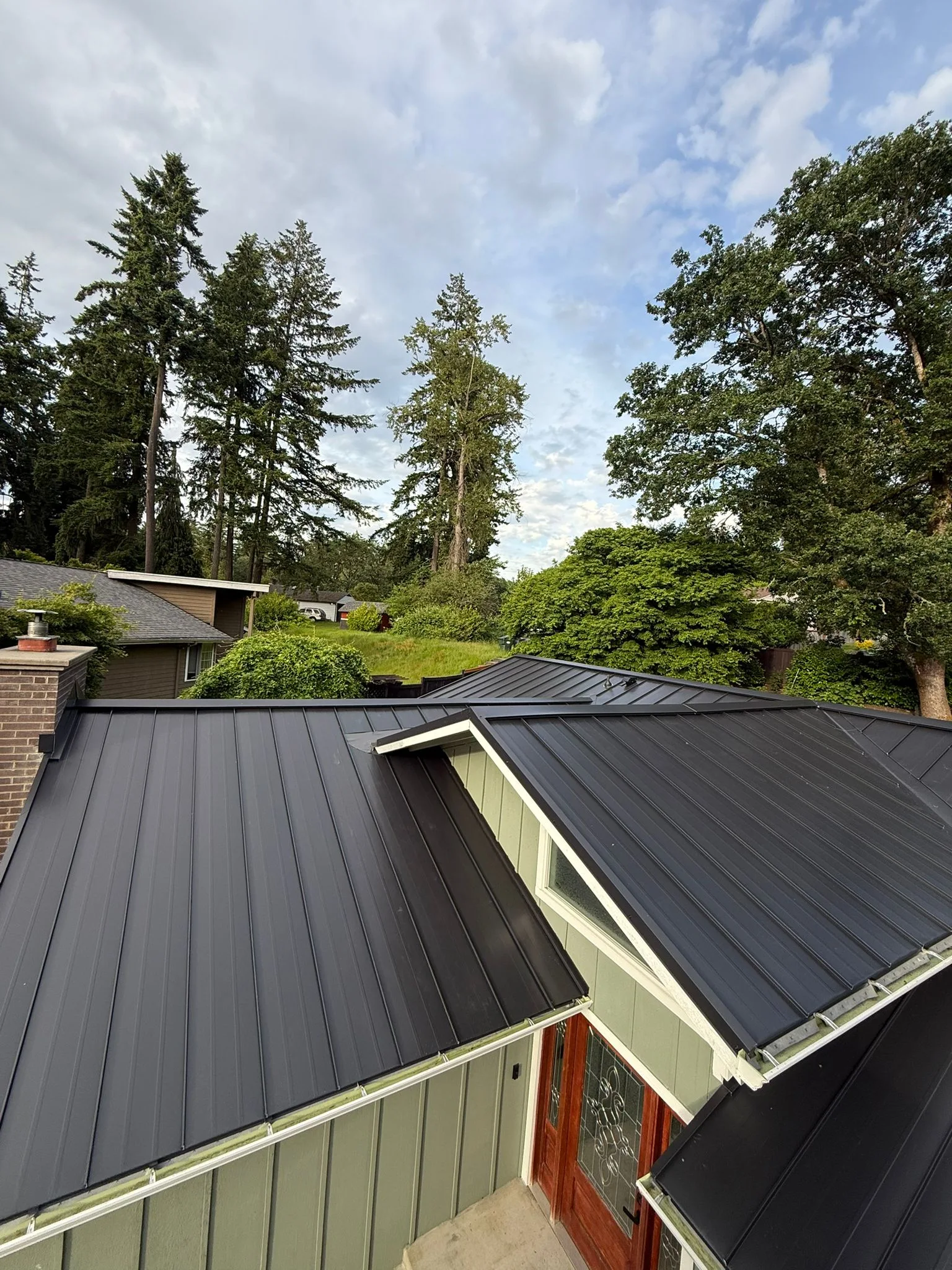 Black Interlock Standing Seam aluminum roof on a home with a black metal roof among trees in a forested, Lakewood, Washington