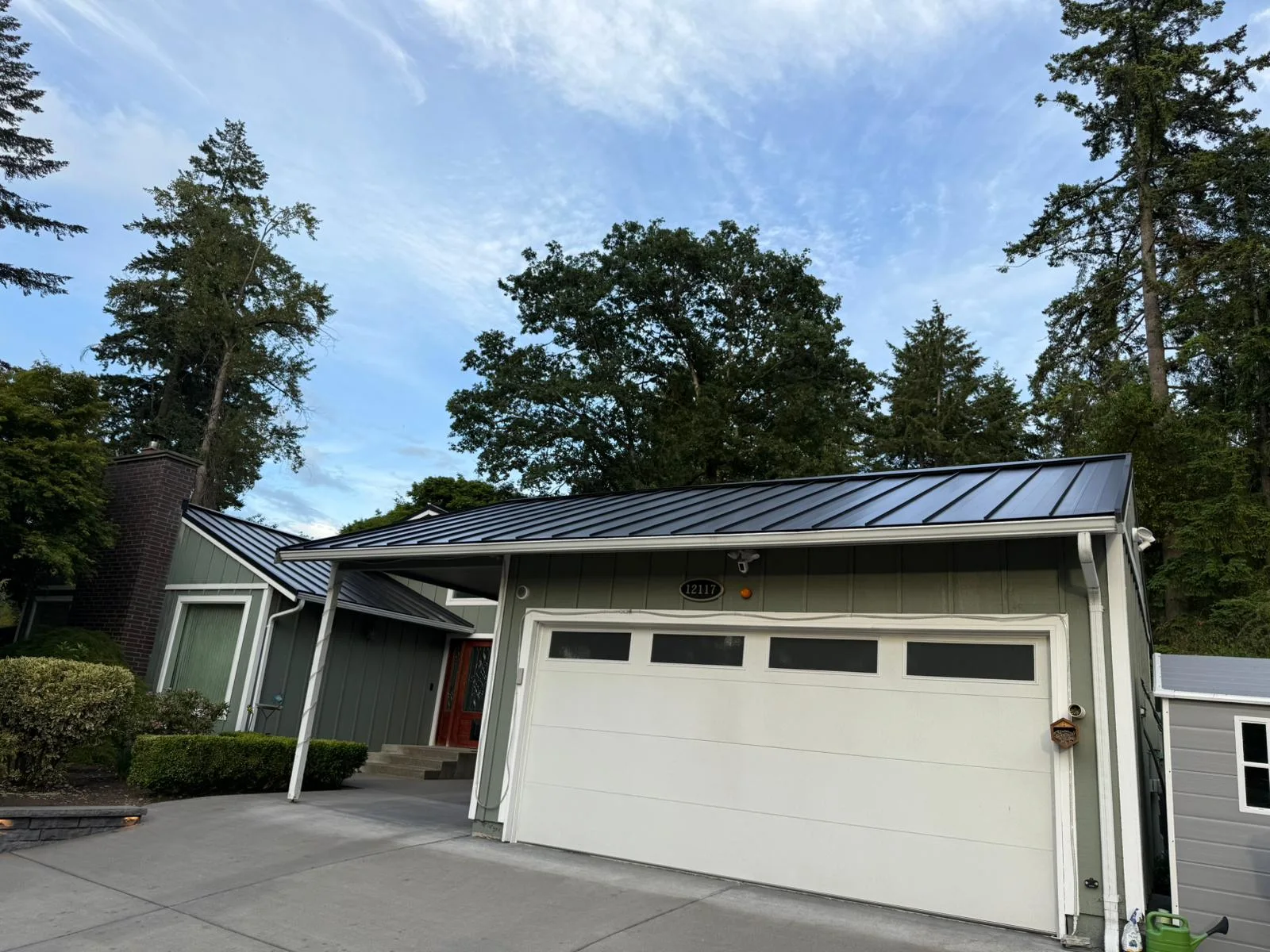 Black Interlock Standing Seam aluminum roof on a green single-family home with a metal roof in a forested, Lakewood, Washington
