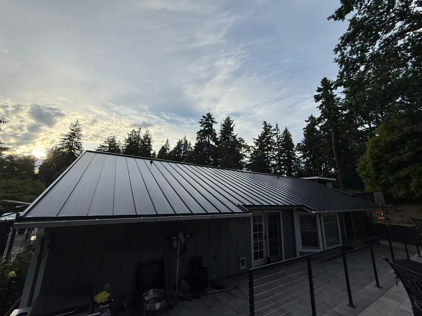 Black Interlock Standing Seam aluminum roof on a black ranch style home among tall trees, Lakewood, Washington