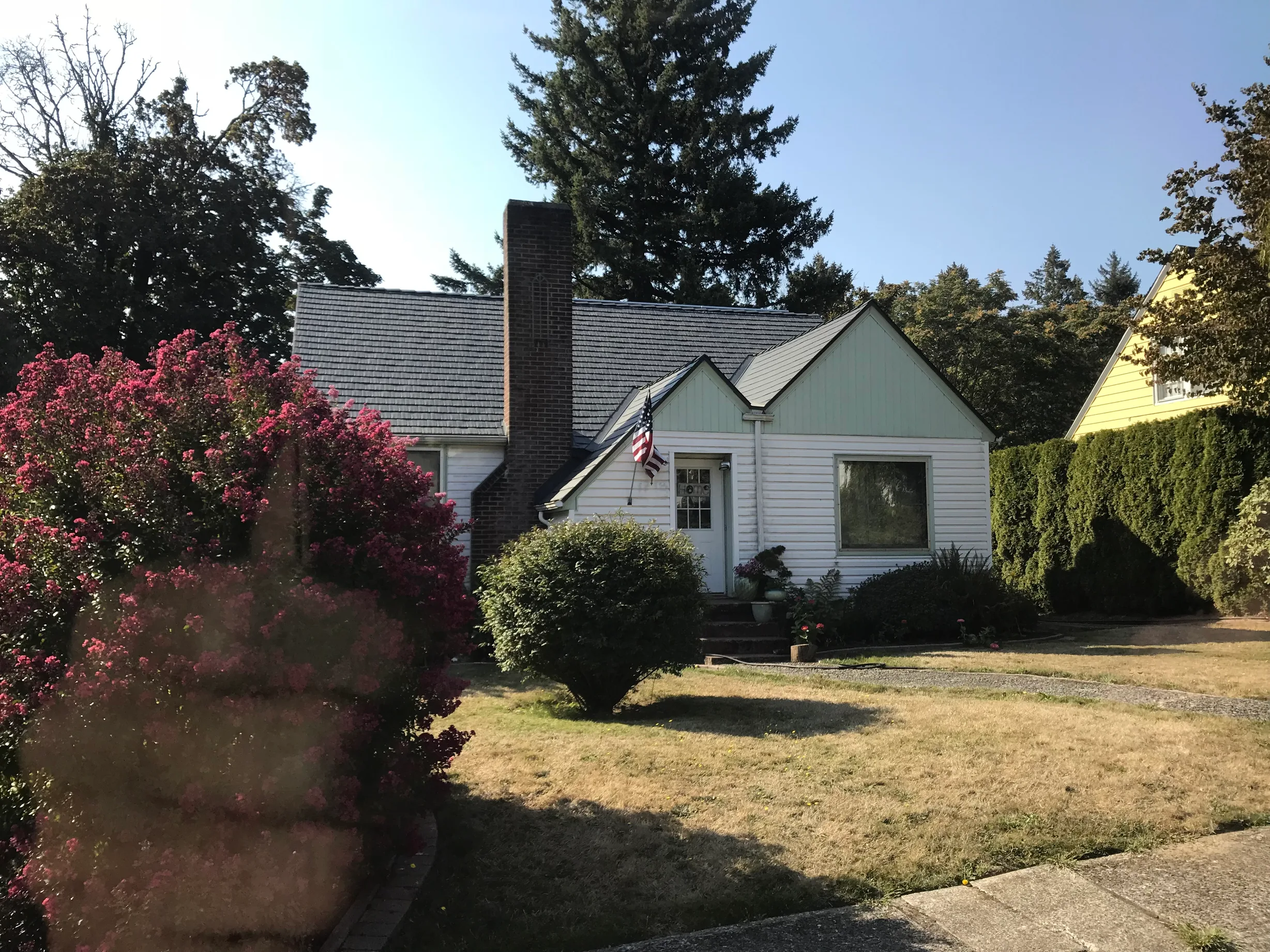 Deep Charcoal Interlock Cedar Shingle aluminum roof on a white one-storey home with dormers in a forested suburban, Camas, Washington