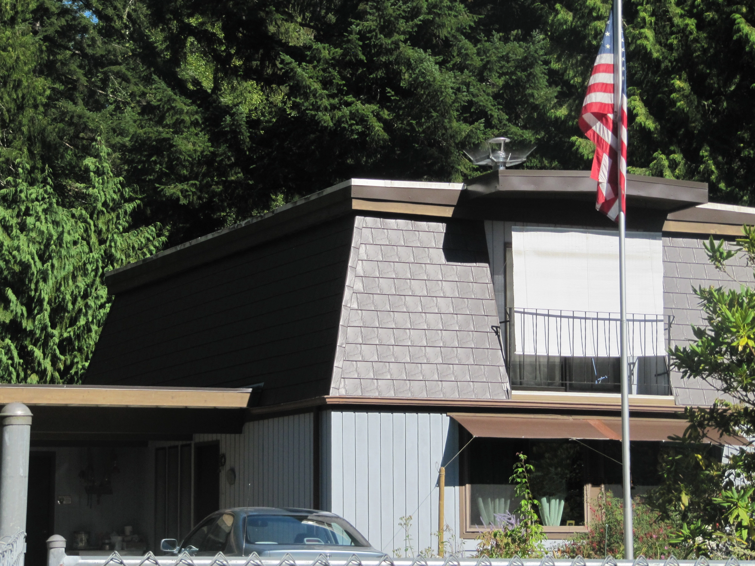 Tudor Brown Interlock Slate aluminum roof on a Tudor-style home with a metal roof in a forested suburban, Allyn, Washington