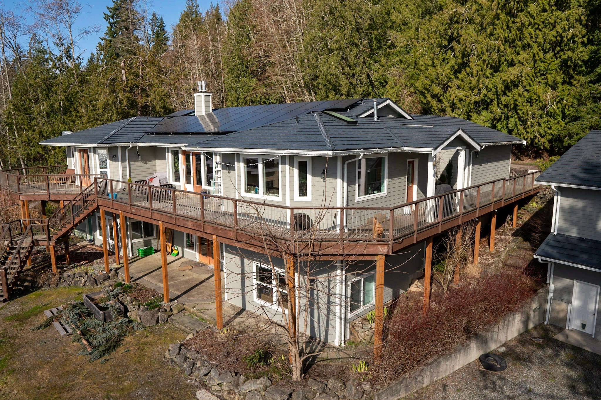 Deep Charcoal Interlock Shake aluminum roof on a grey ranch home with a metal roof on a forested slope, Bellingham, Washington