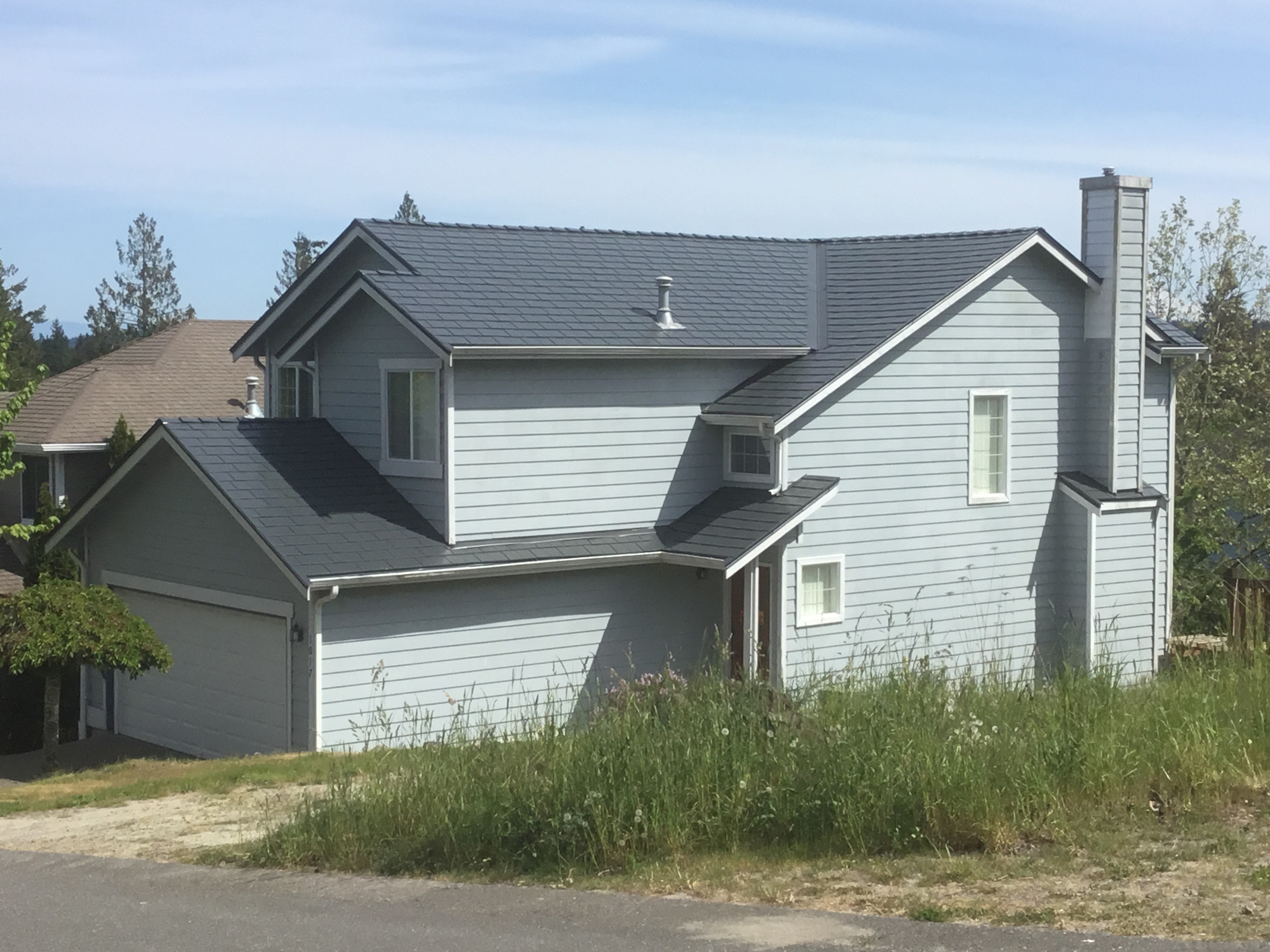 Two-story craftsman home in Silverdale, WA featuring Interlock aluminum slate roofing in Deep Charcoal, with dormer, chimney, and complex multi-gable roof.