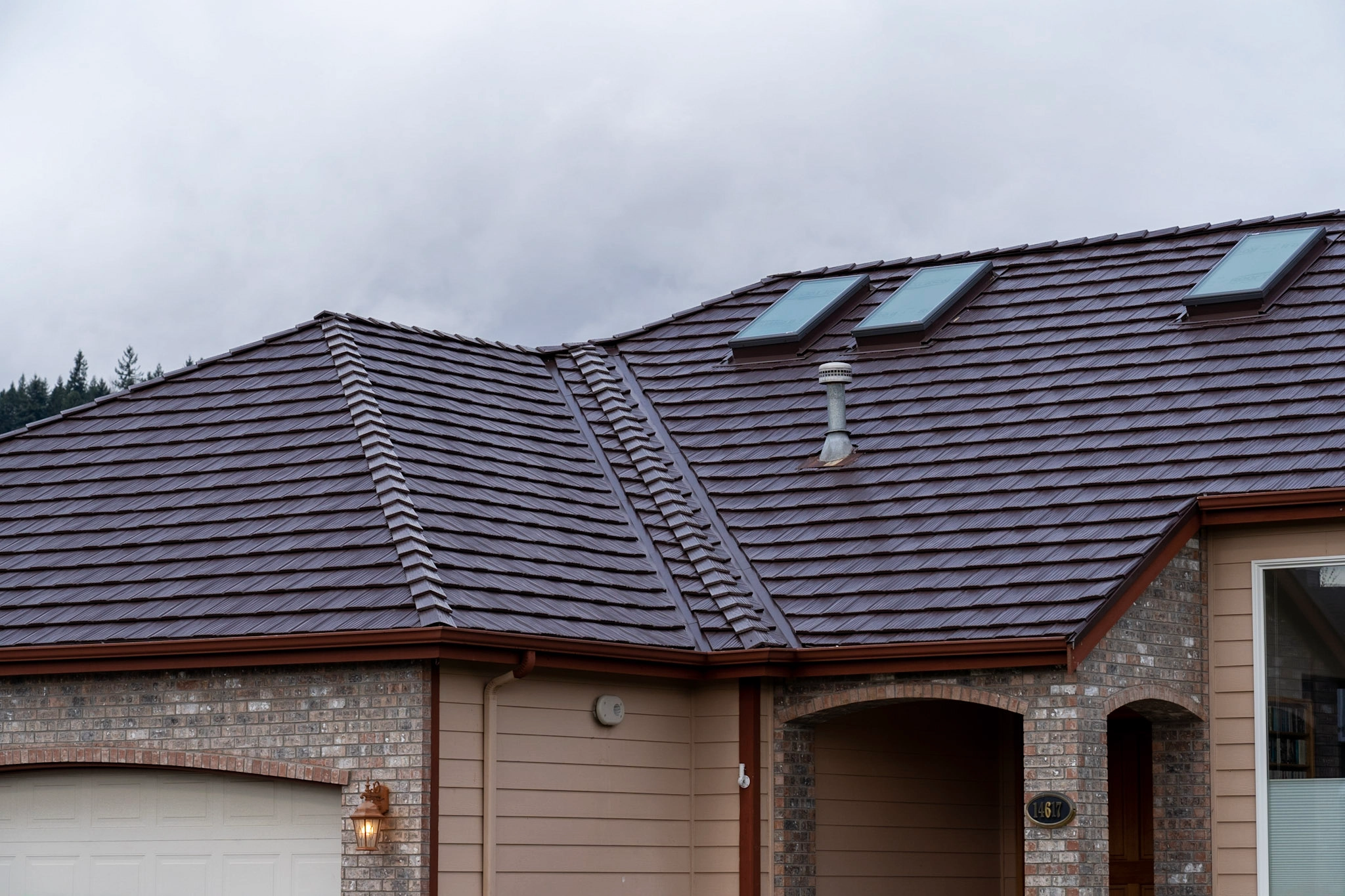 Colonial Brown Interlock Shake aluminum roof on a tan single-storey home with Colonial style among trees, Orting, Washington