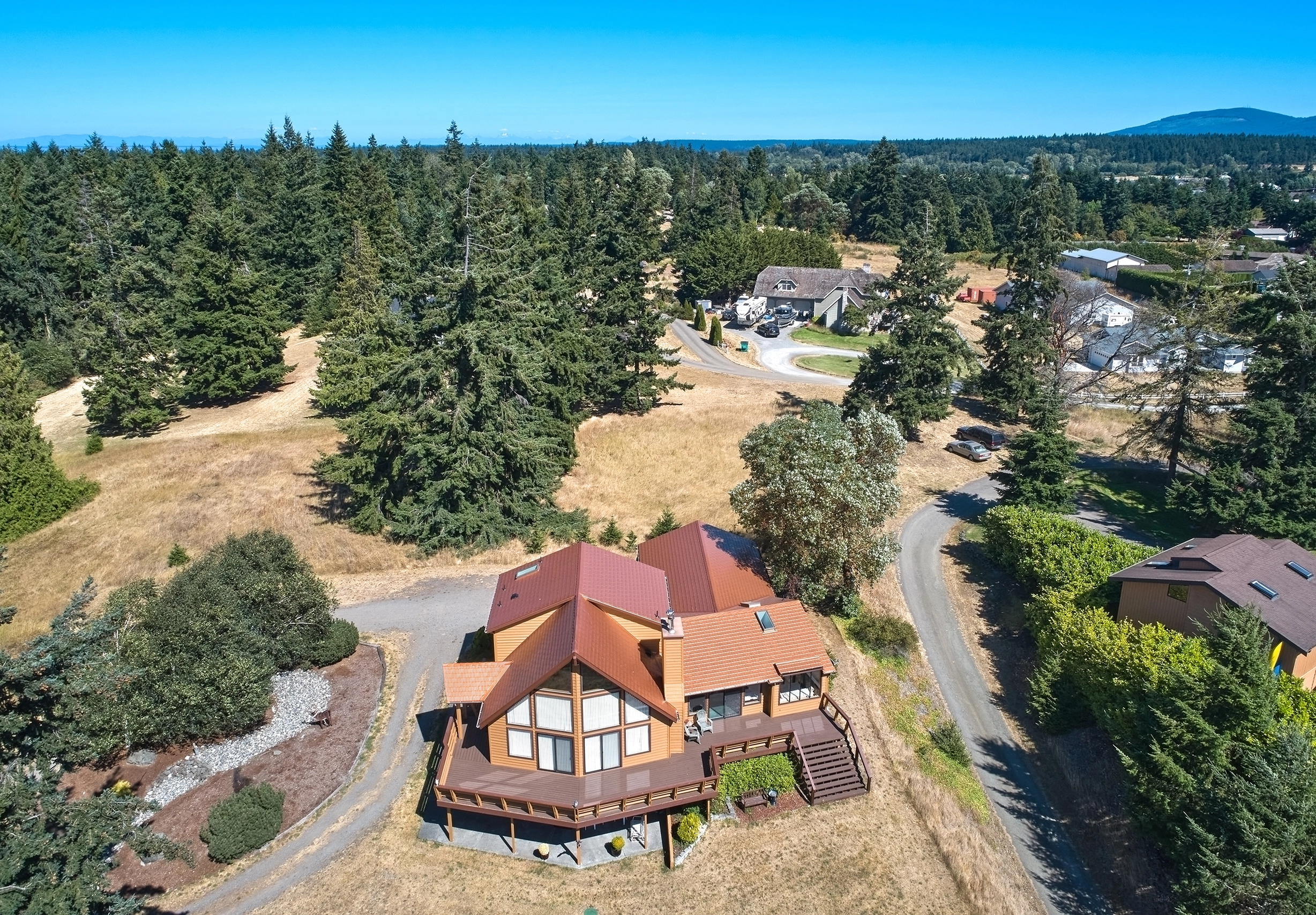 Copper Penny Interlock Cedar Shingle aluminum roof on a two-storey chalet among tall pines in Sequim, Washington, Sequim, Washington