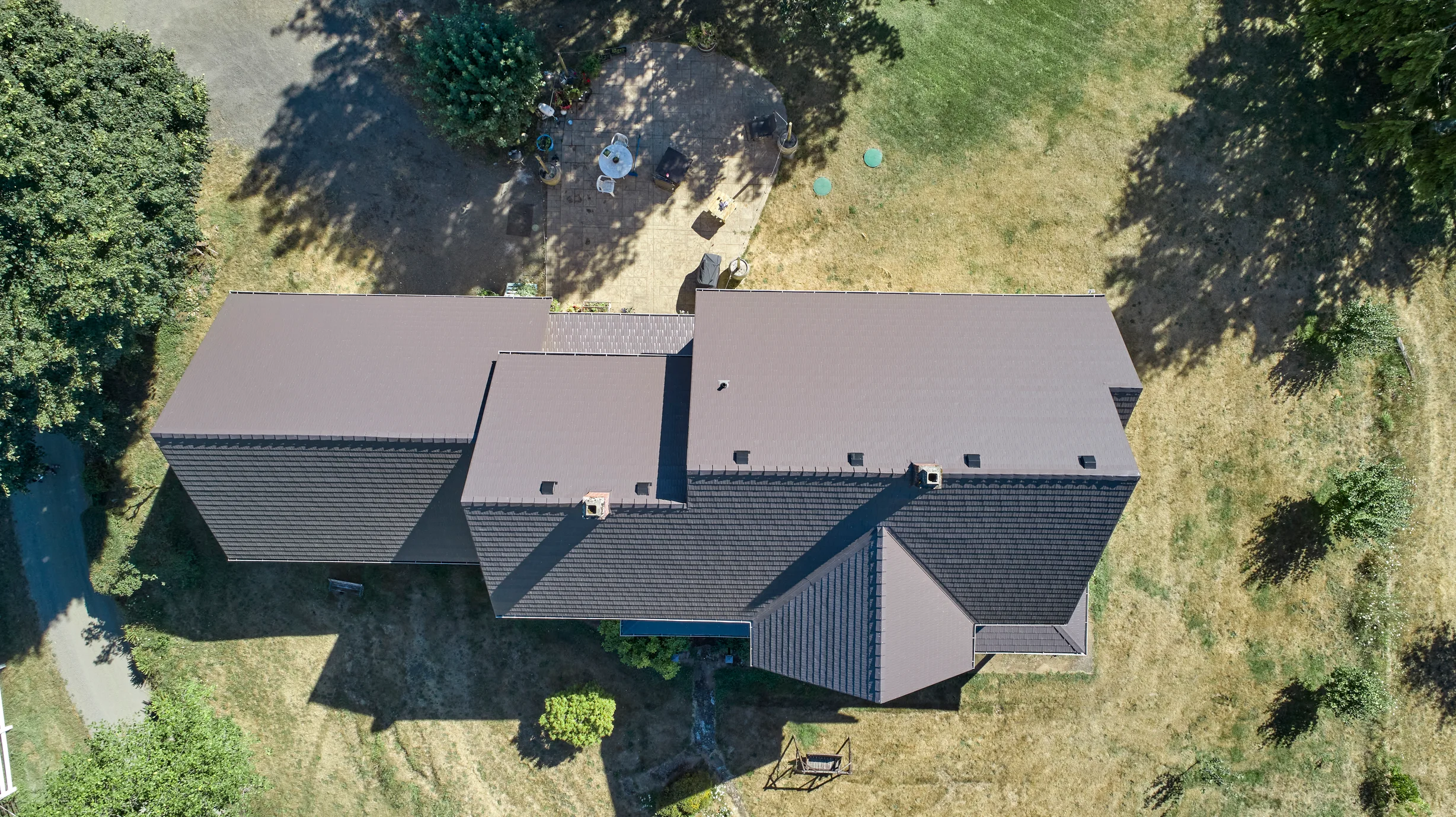 Black Interlock Slate aluminum roof on a black home with a metal roof among tall trees, Longview, Washington
