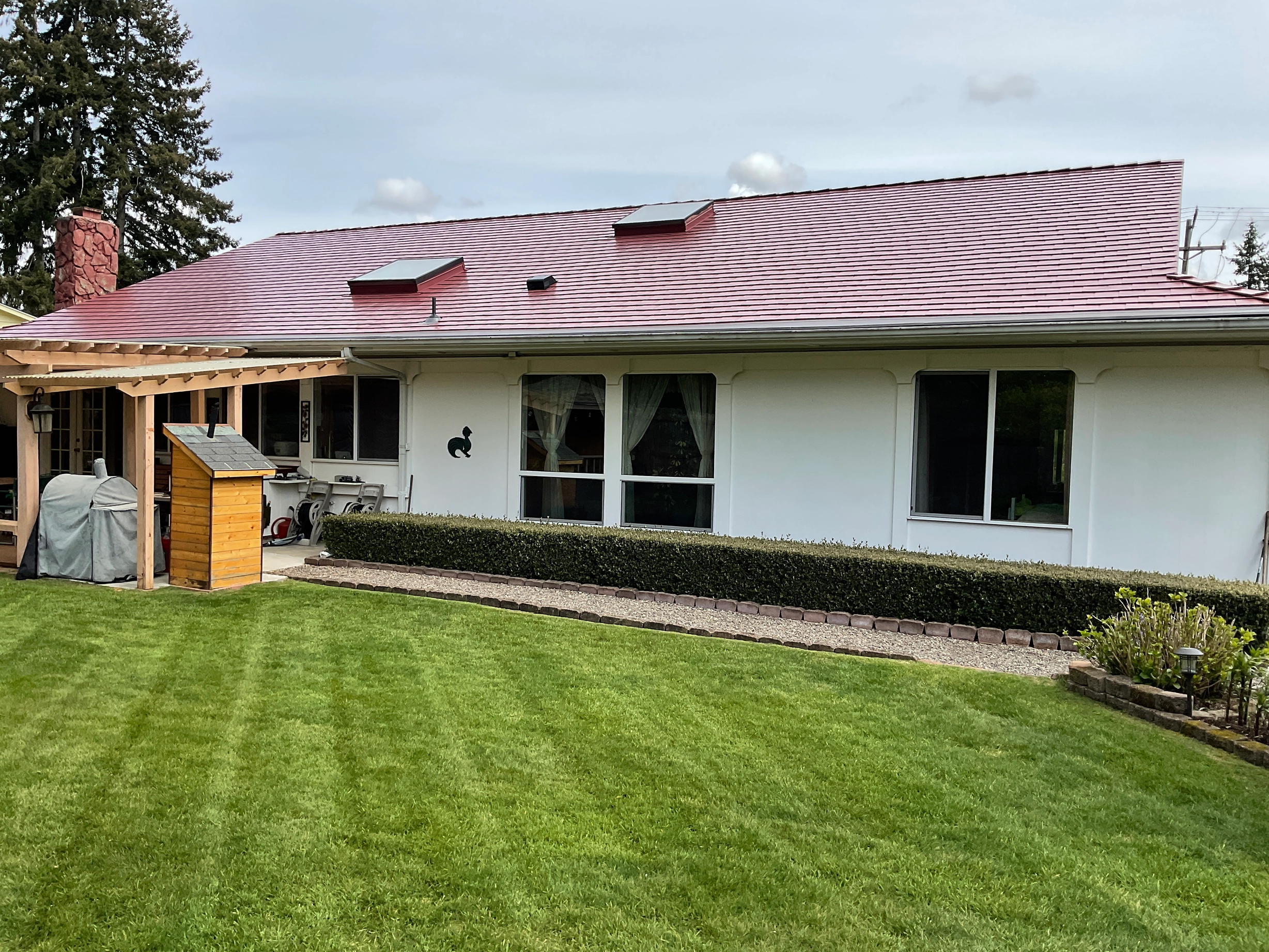 Tile Red Interlock Slate aluminum roof on a white one-storey home with a red metal roof in a, Lakewood, Washington