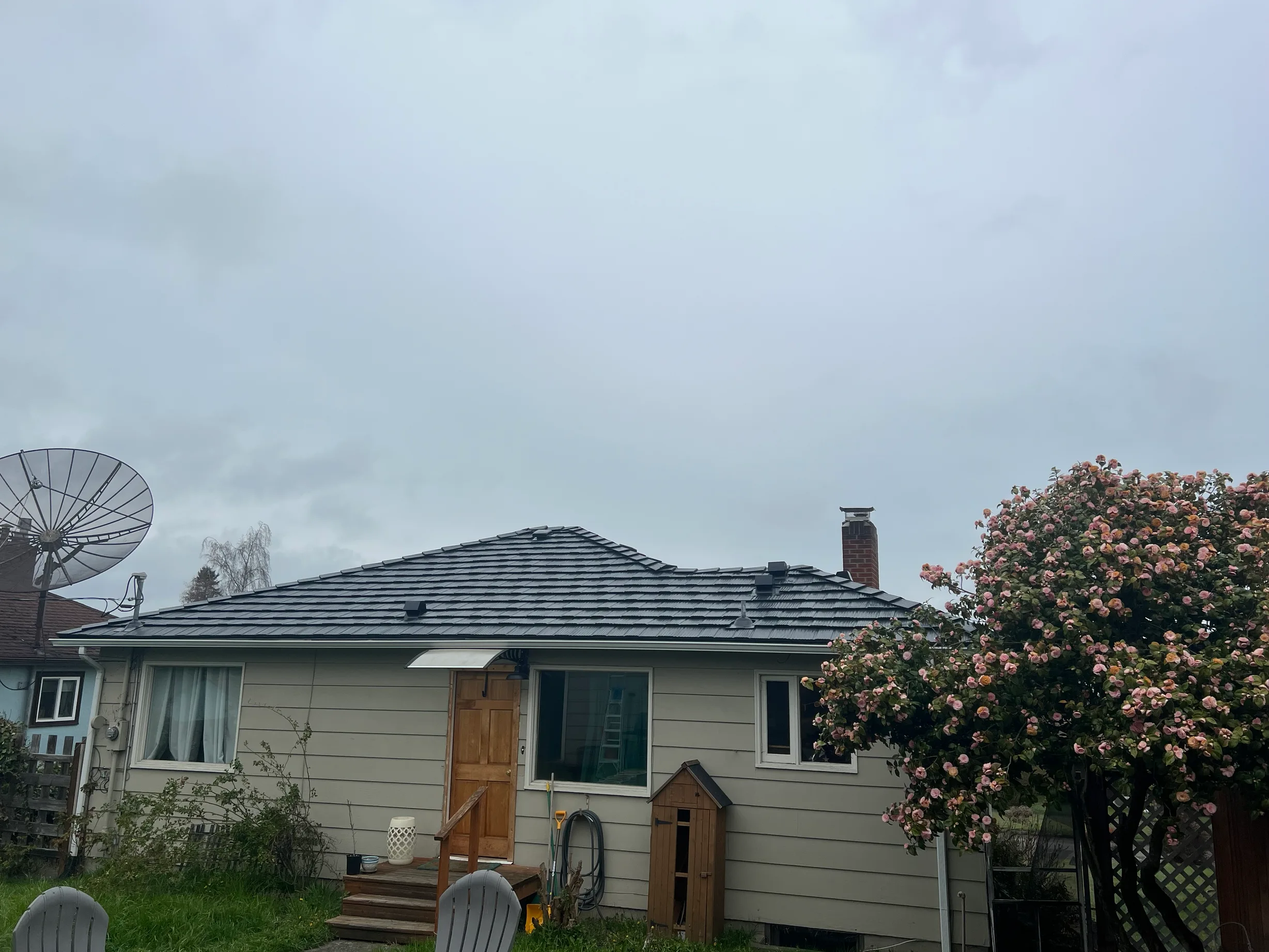 Black Interlock Shake aluminum roof on a beige one-storey home with dormers and a large tree, Port Angeles, Washington