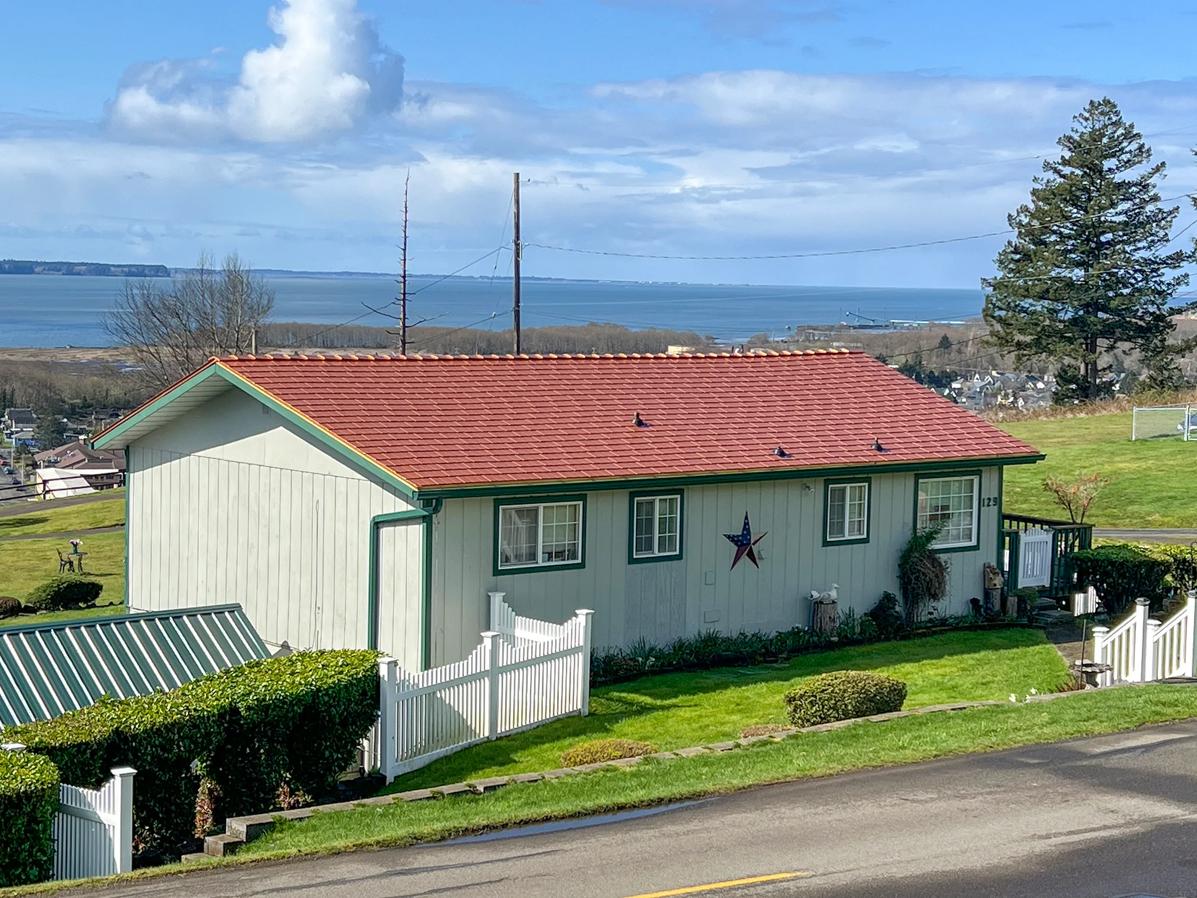 Copper Penny Interlock Cedar Shingle aluminum roof on a white home with green trim and a red roof on a grassy hill, Hoquiam, Washington