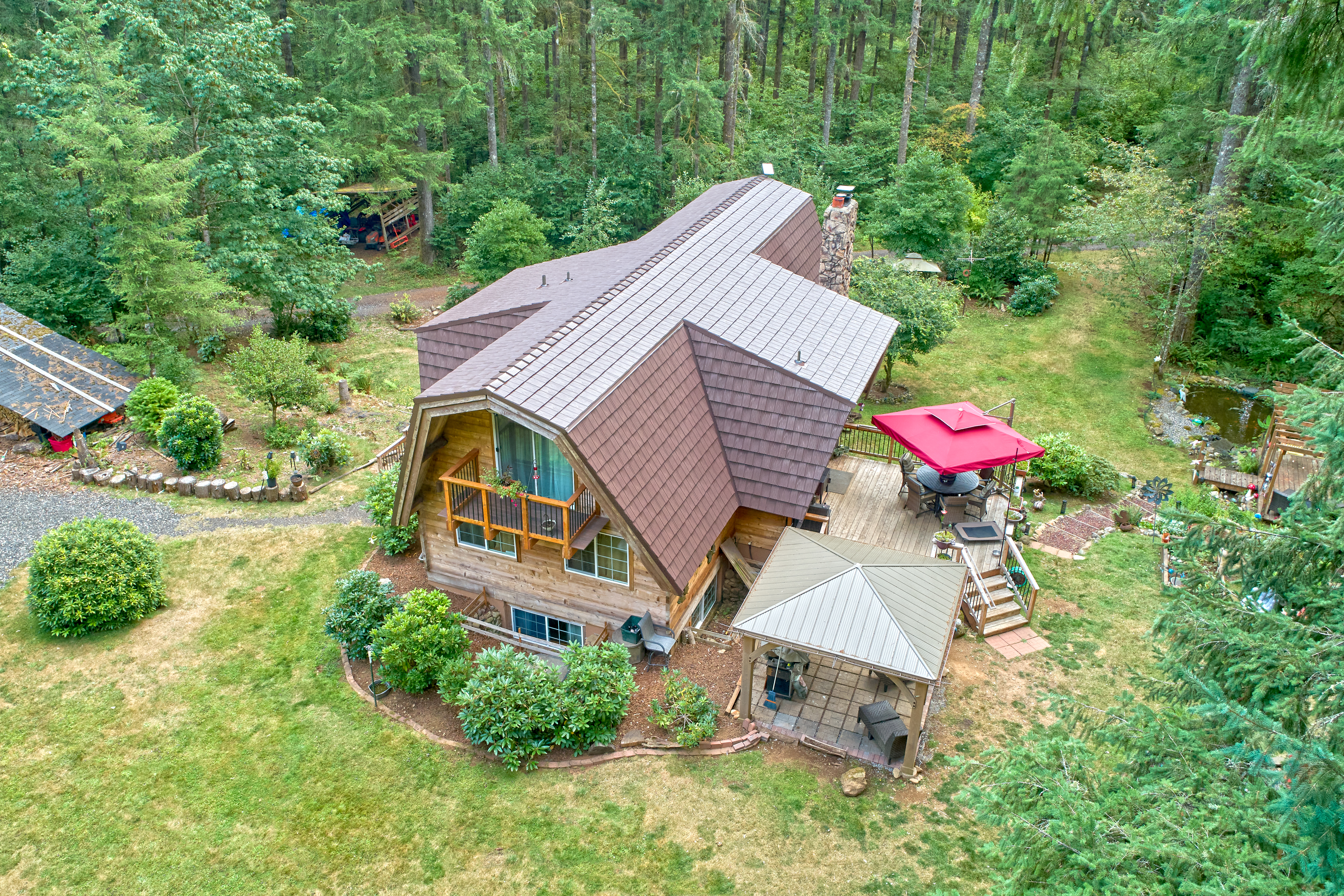 Aerial view of a chalet-style home in Yacolt, WA featuring Interlock aluminum shake roofing in Colonial Brown with steep multi-plane roof and stone chimney.