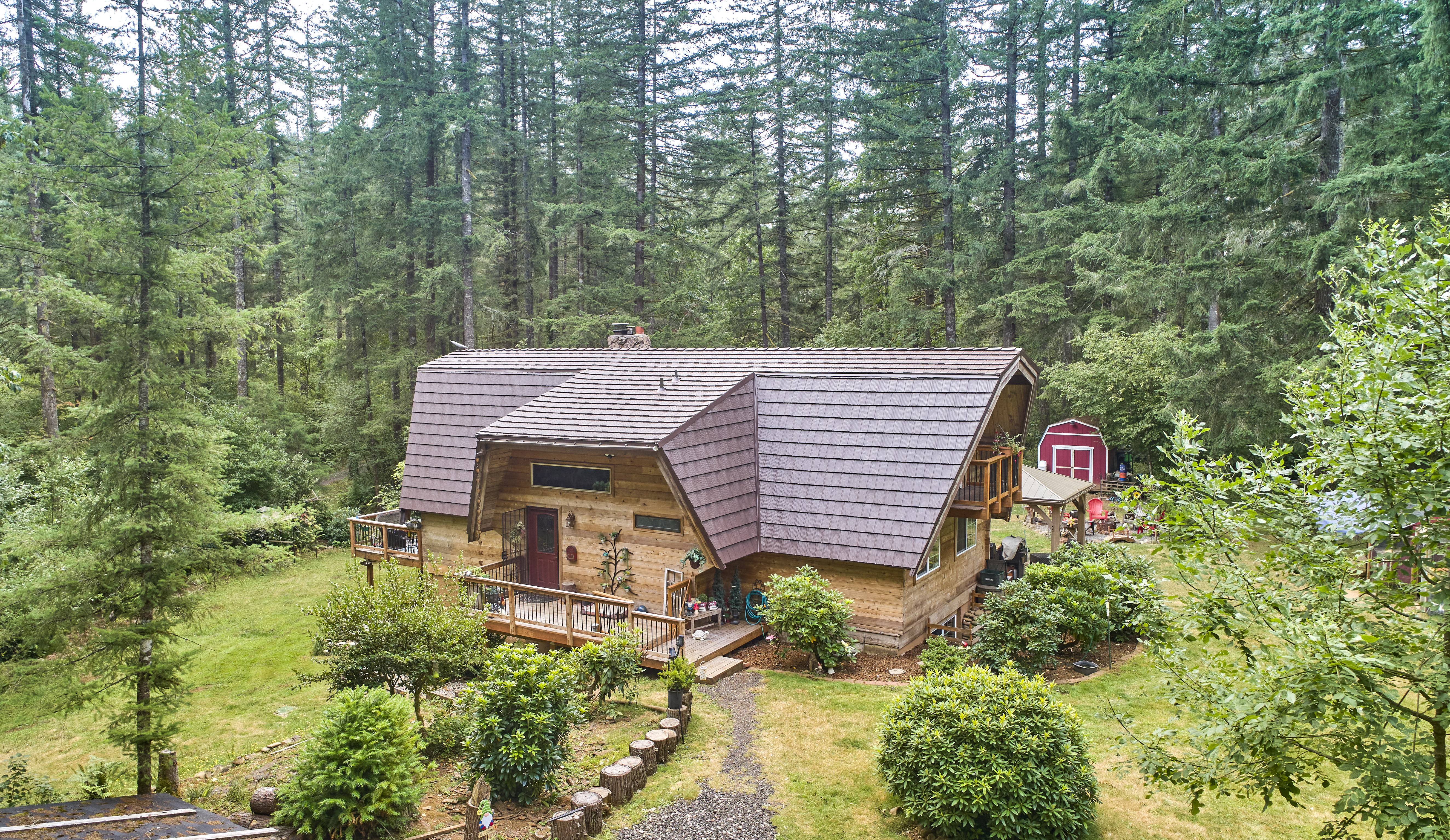 Aerial view of a forested chalet-style home in Yacolt WA with steep Interlock aluminum shake roofing in Colonial Brown and a prominent chimney.