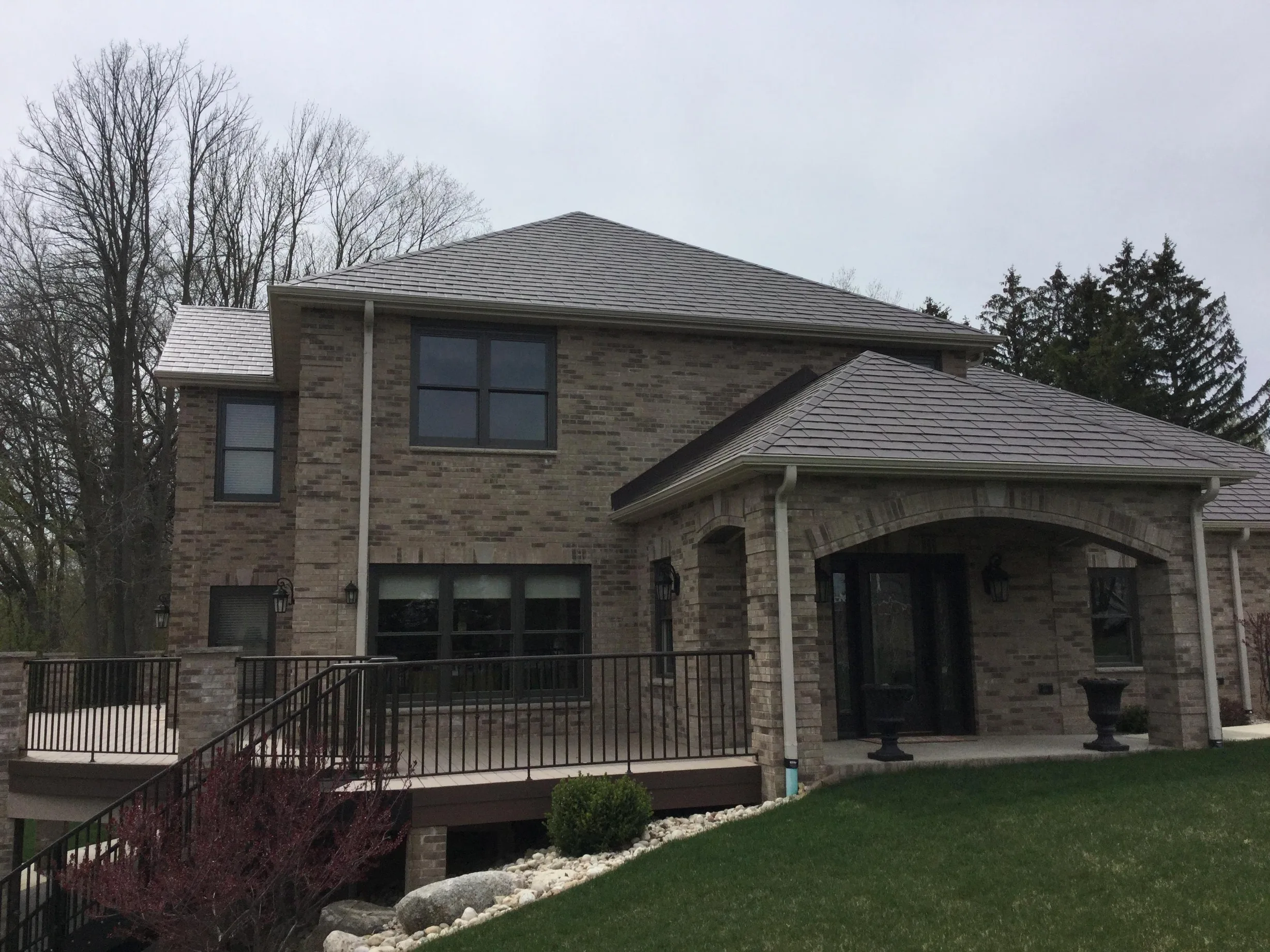 Colonial Brown Interlock Slate aluminum roof on a brown two-storey home with a metal roof and stone facade, Horicon, Wisconsin