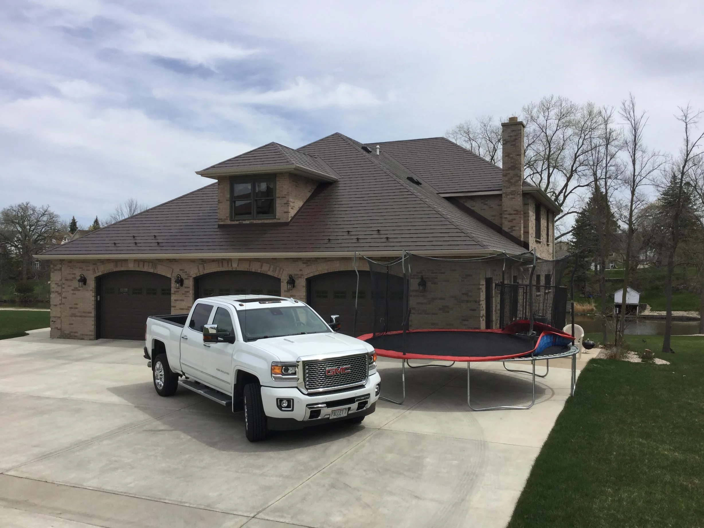 Colonial Brown Interlock Slate aluminum roof on a brown two-storey Colonial home with dormers among tall, Horicon, Wisconsin
