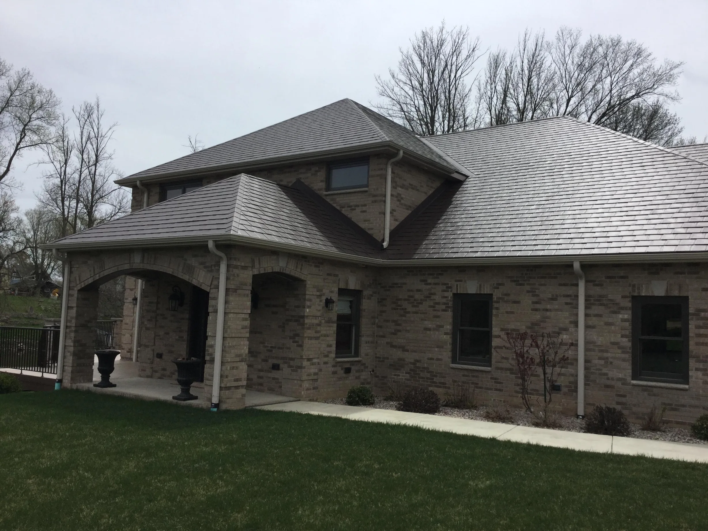 Colonial Brown Interlock Slate aluminum roof on a brown Colonial home with dormers in a wooded area, Horicon, Wisconsin