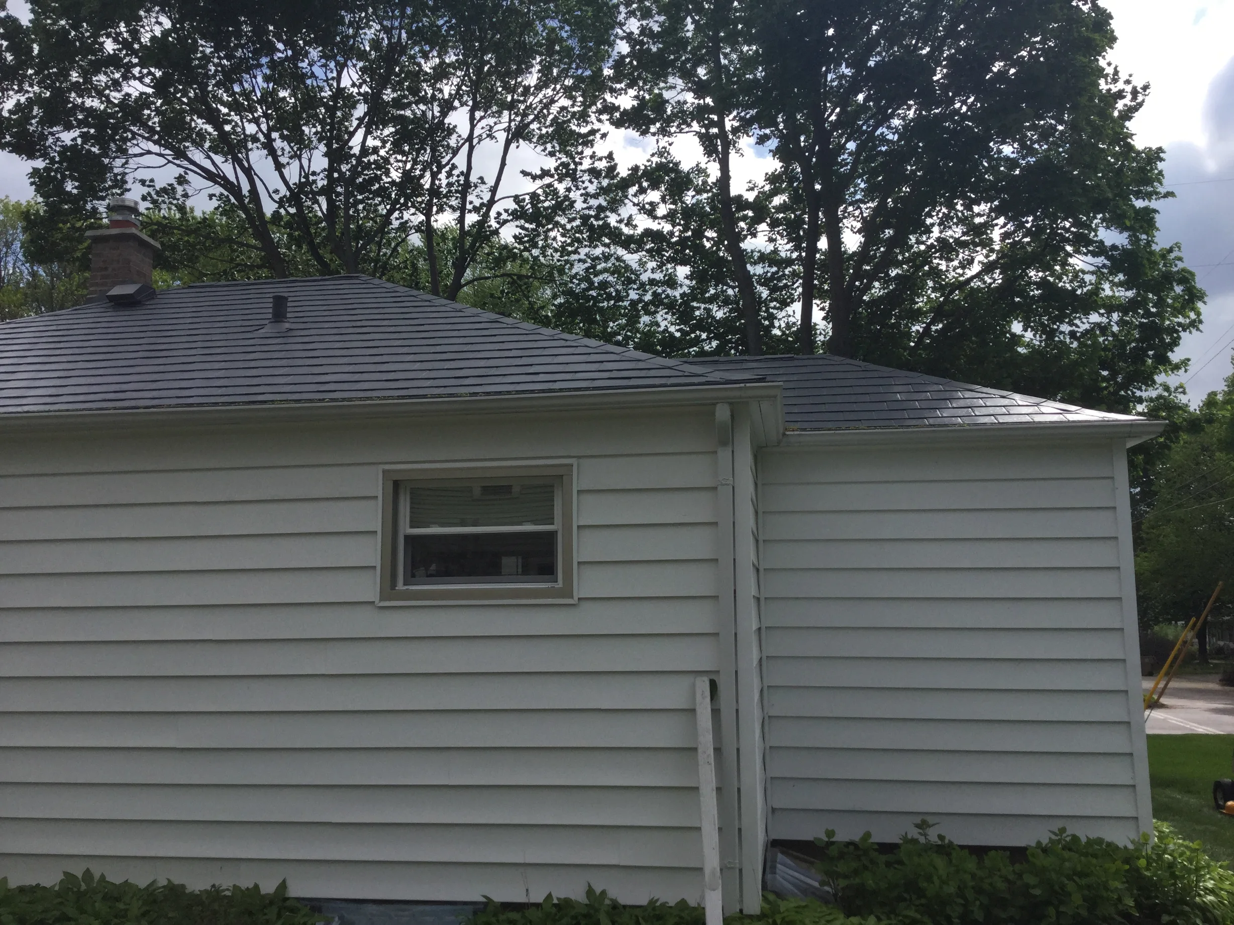 Charcoal Grey Interlock Slate aluminum roof on a white one-storey ranch home with a metal roof among tall, Madison, Wisconsin