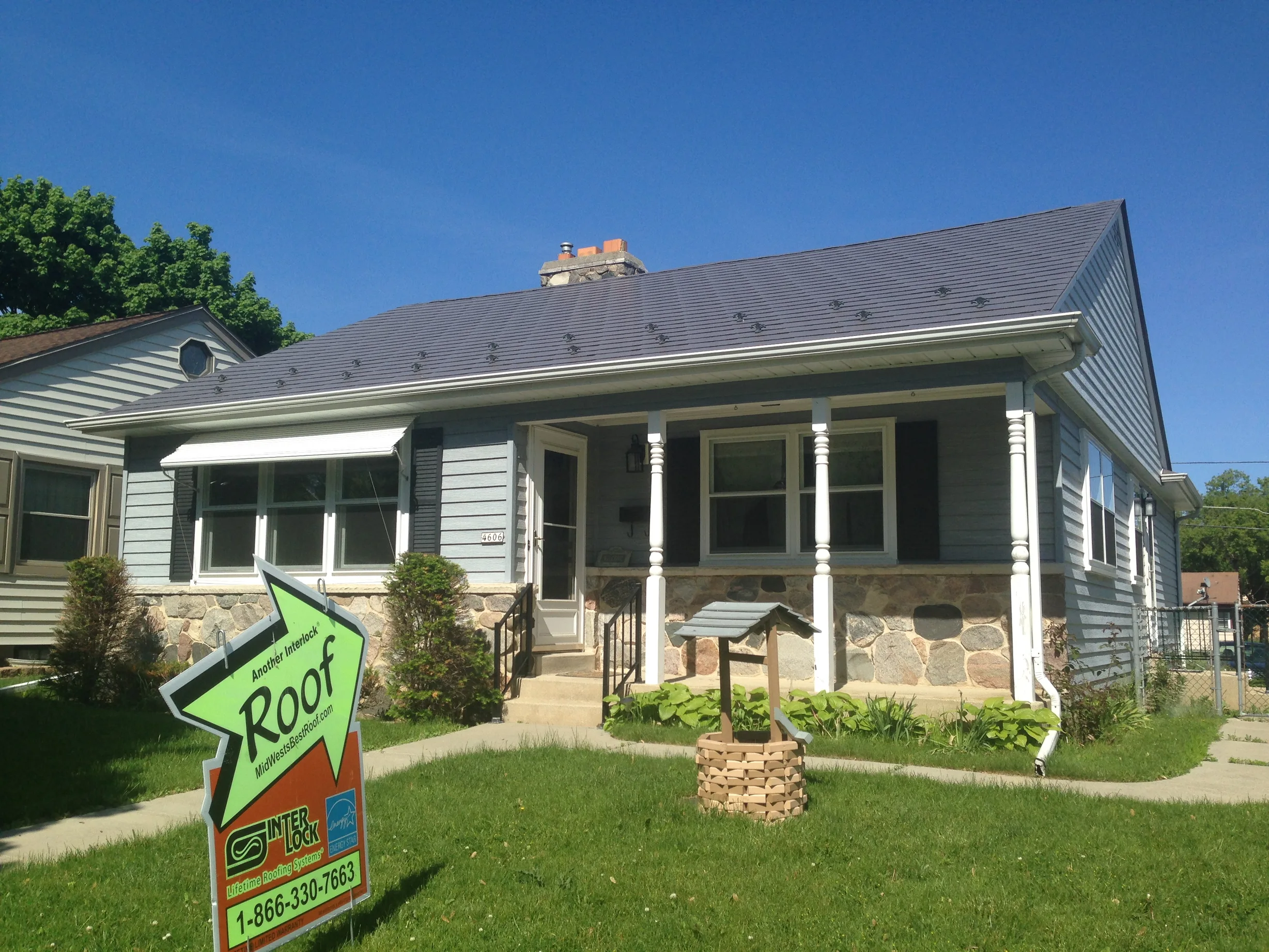 Weathered Interlock Slate aluminum roof on a light blue ranch home with a stone front among green lawns, Milwaukee, Wisconsin